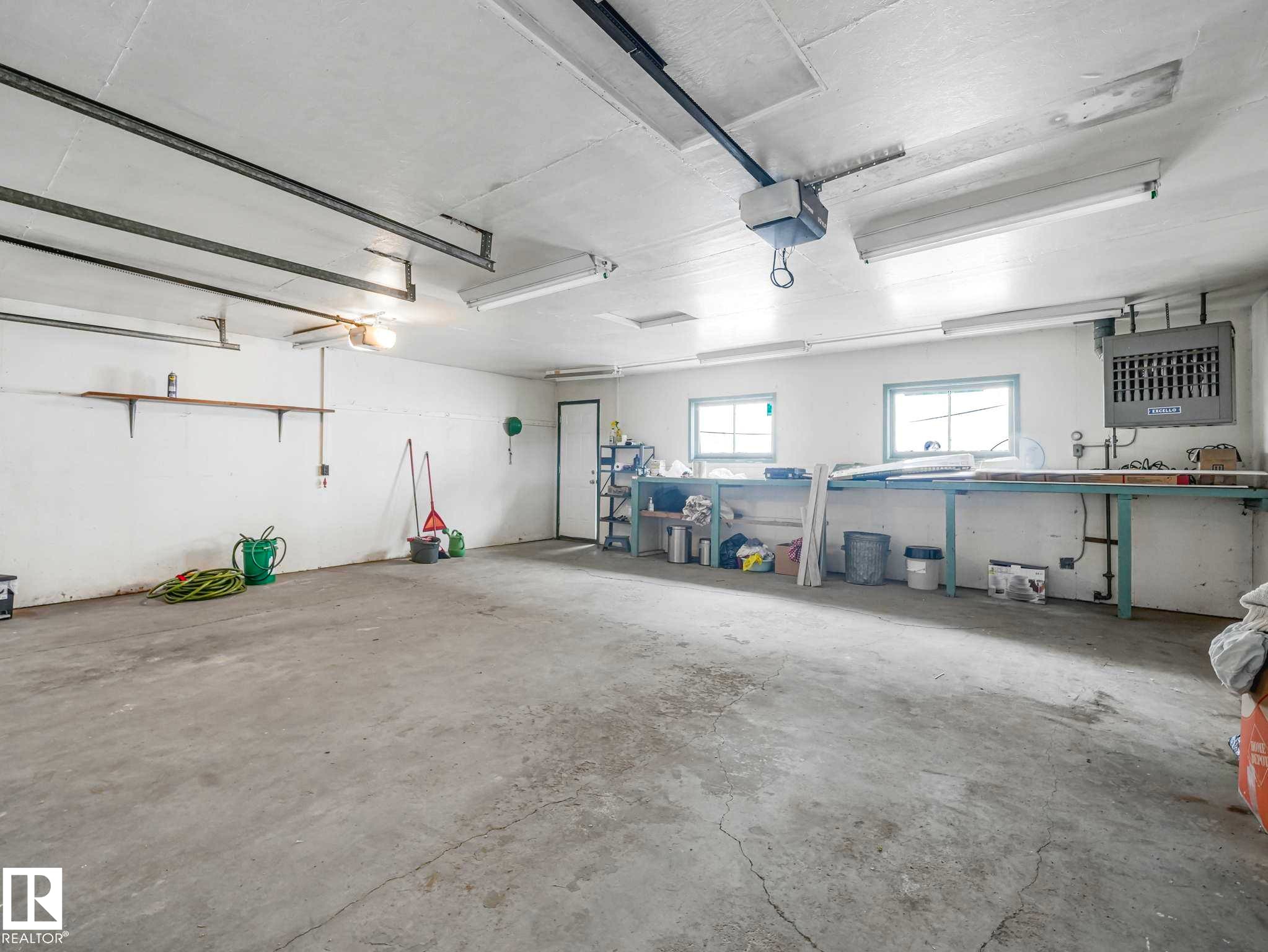 Concrete flooring, wall-mounted shelving, built-in workbench, multiple windows, and overhead lighting - 15916 88B Avenue Nw, Edmonton, AB