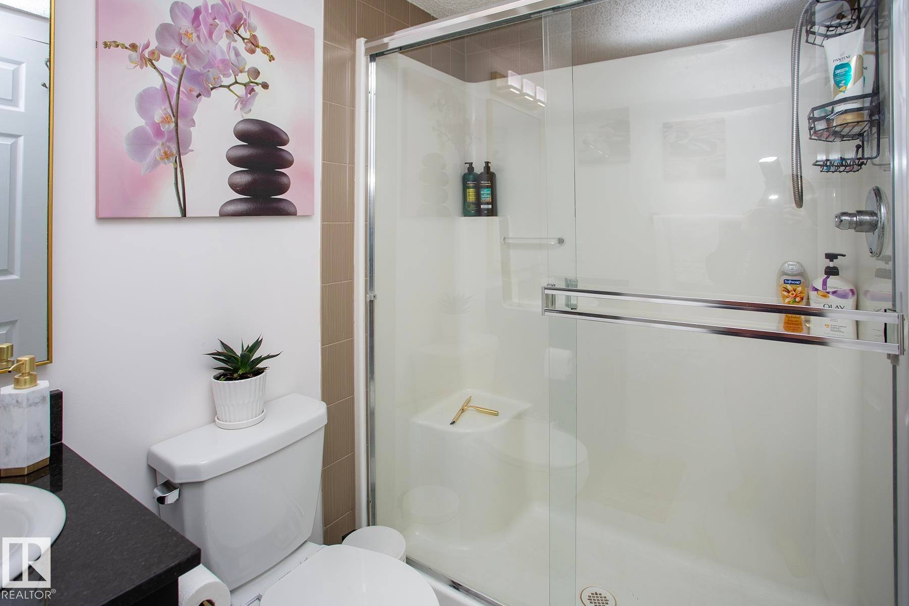 Walk-in shower with a glass enclosure, white shower base, and integrated shelving - #201 1070 Mcconachie Bv Nw, Edmonton, AB