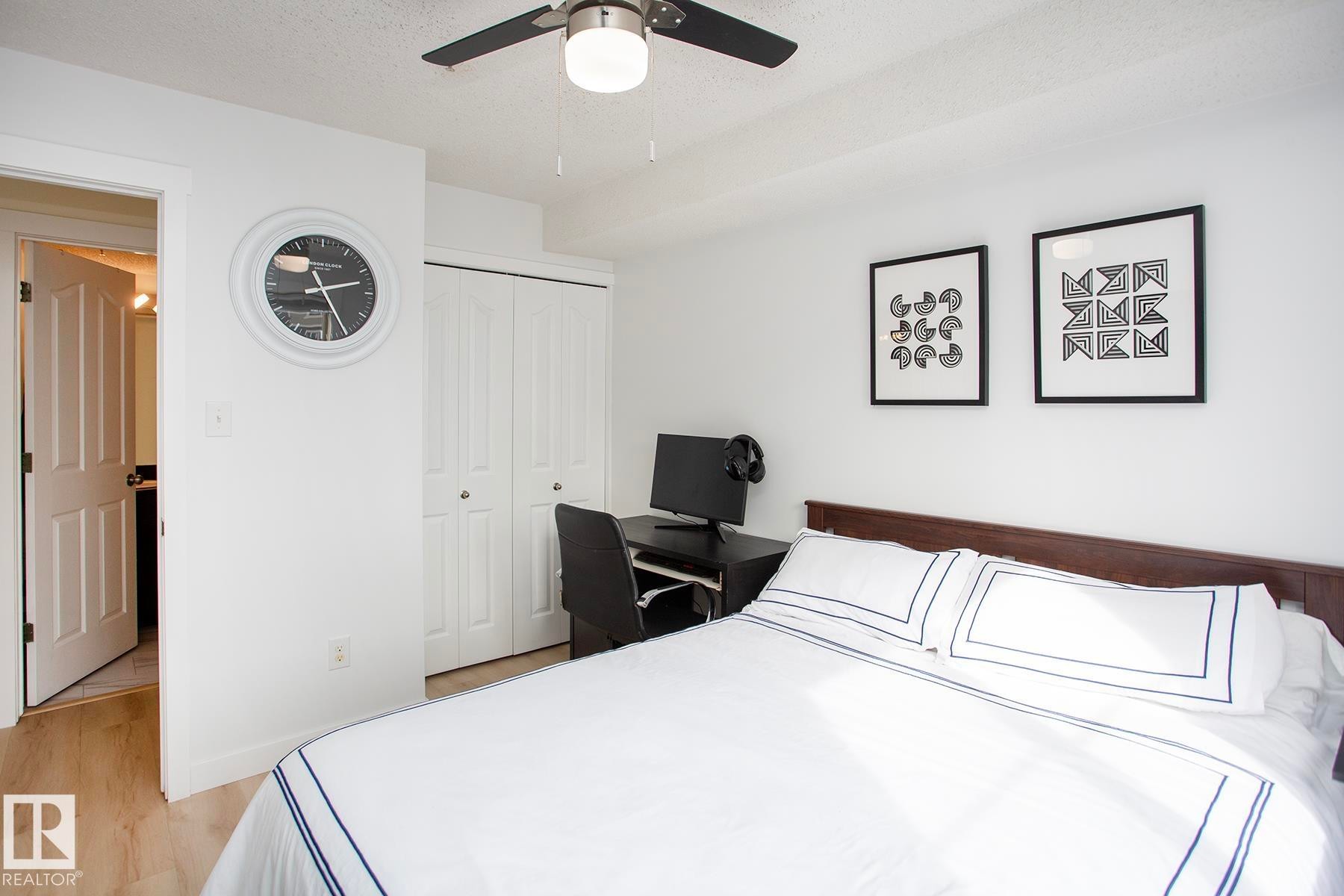 Wood-finish flooring, ceiling fan, white bi-fold closet doors, and a wood headboard - #201 1070 Mcconachie Bv Nw, Edmonton, AB