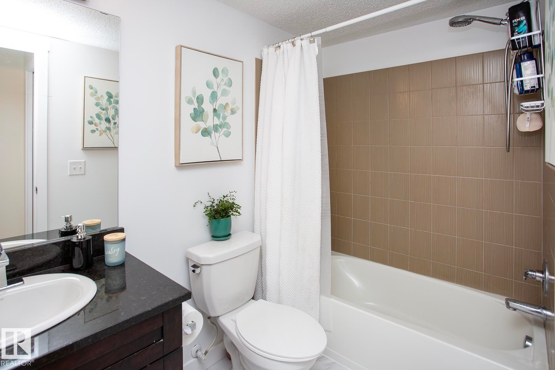 Built-in bathtub with subway tile surround, chrome fixtures, and a shower head - #201 1070 Mcconachie Bv Nw, Edmonton, AB