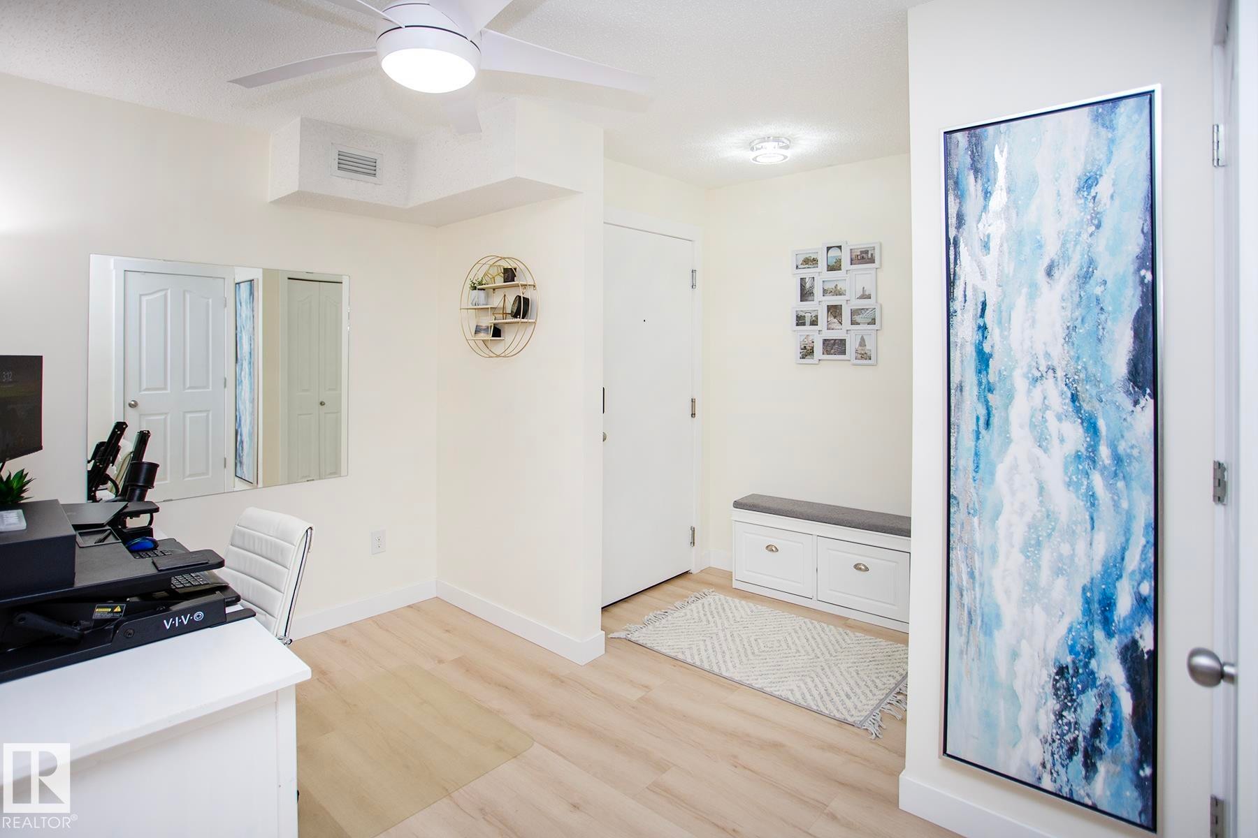 Light wood-finish flooring throughout, complemented by a ceiling fan with integrated lighting - #201 1070 Mcconachie Bv Nw, Edmonton, AB