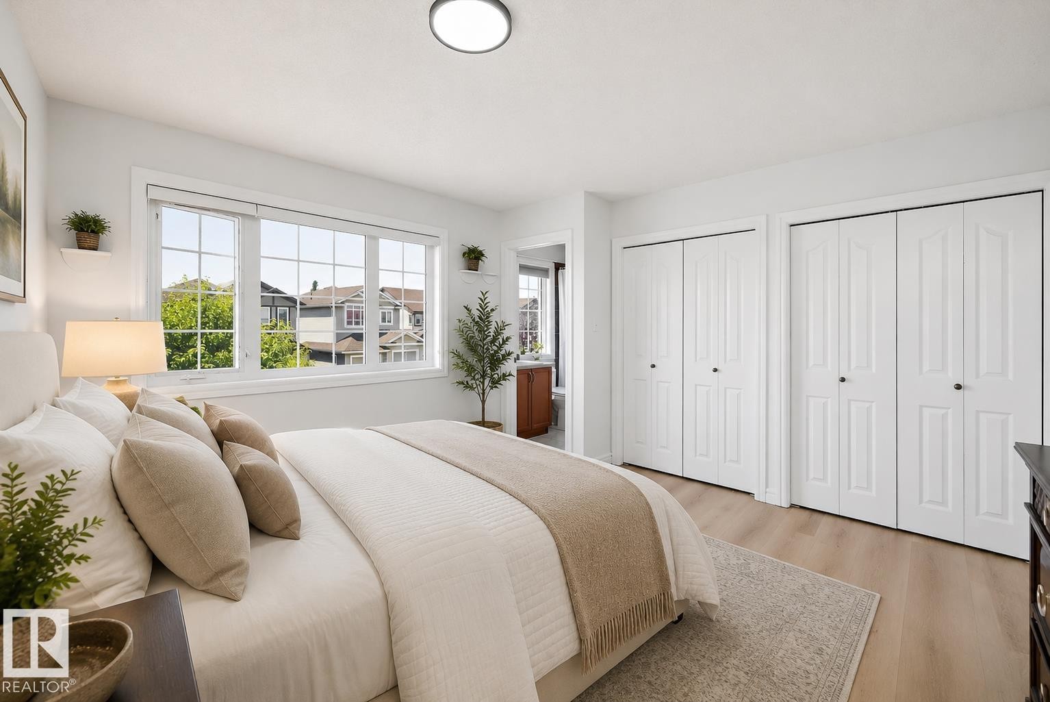 Bedroom featuring light wood-finish flooring, a large multi-pane window, and two sets of white bi-fold closet doors - 2803 12 Street Nw, Edmonton, AB