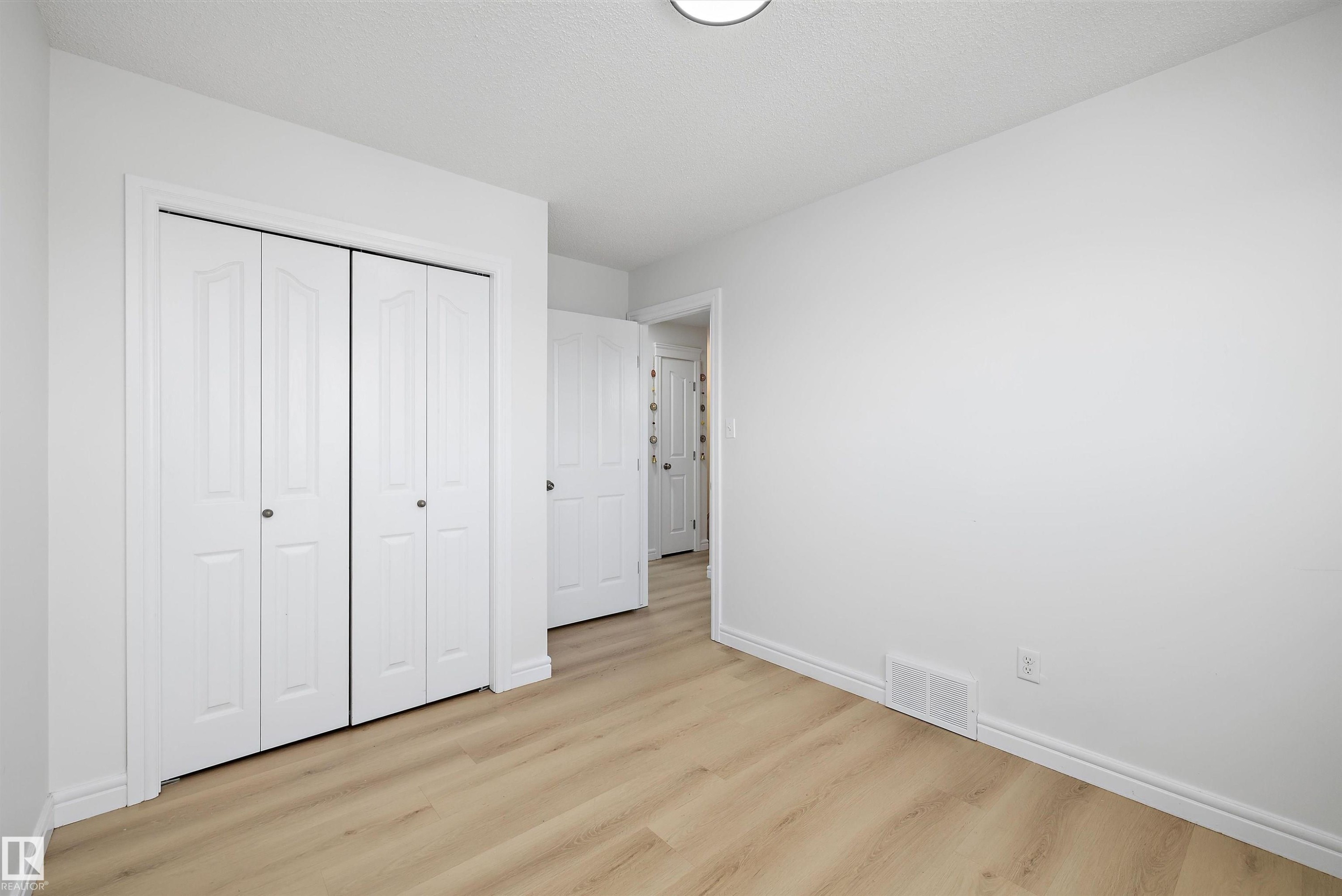 Bright interior space featuring light wood-finish flooring, white walls, and white baseboards - 2803 12 Street Nw, Edmonton, AB