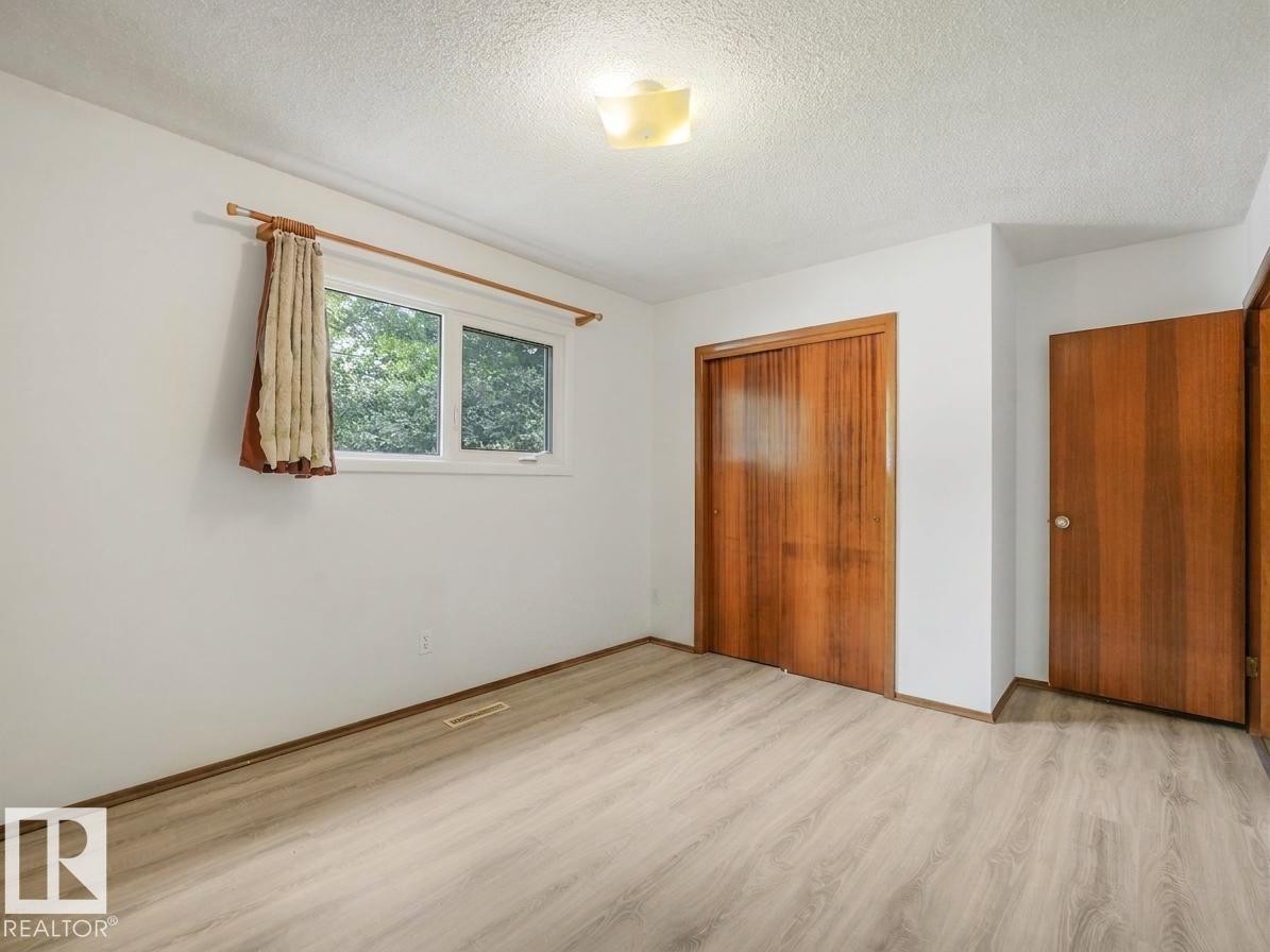 Light wood-finish flooring, white painted walls, natural wood doors, and a ceiling-mounted light fixture - 16428 88 Avenue Nw, Edmonton, AB