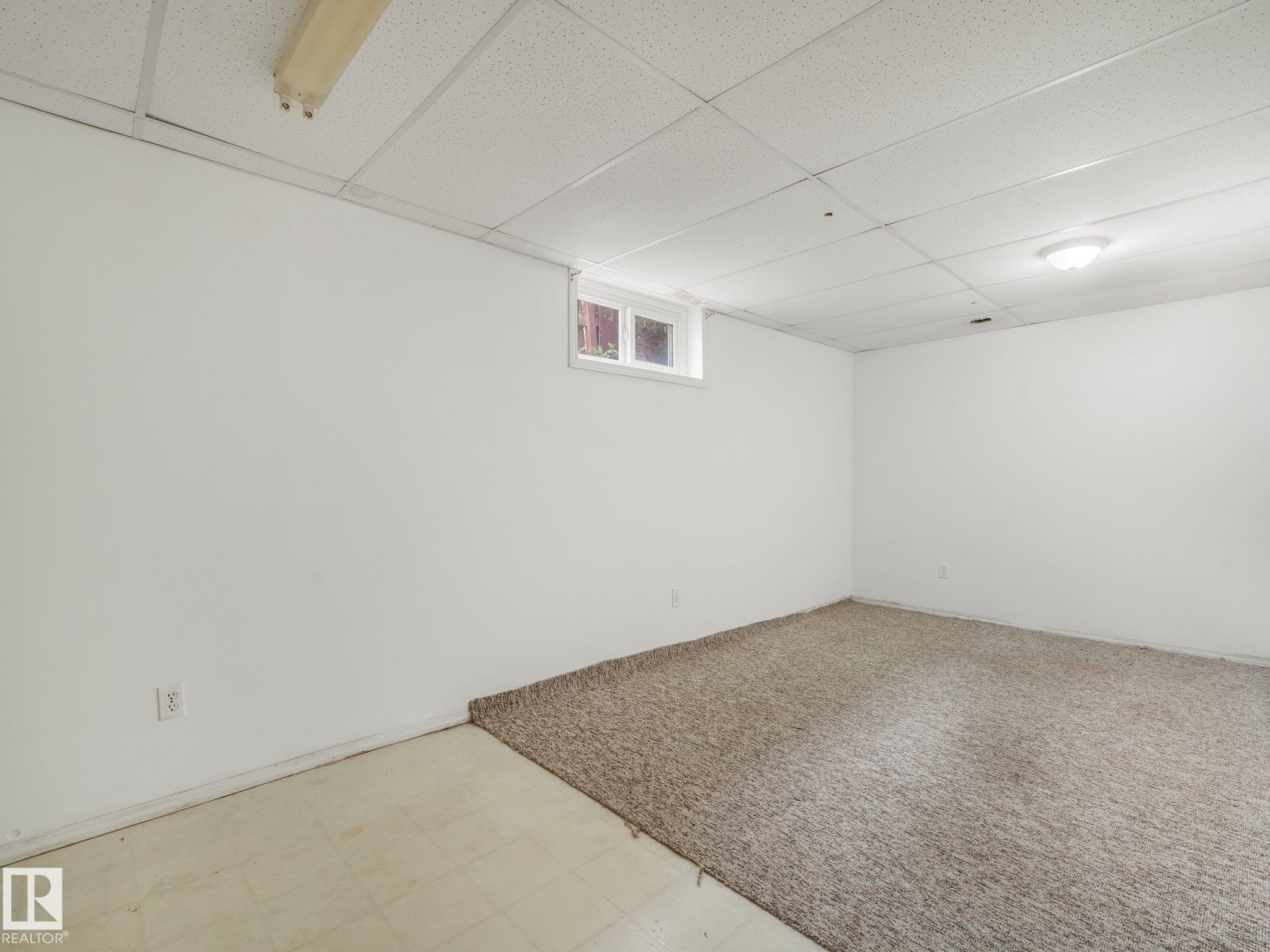White painted walls with a drop ceiling, a window, and two distinct flooring types - 16428 88 Avenue Nw, Edmonton, AB