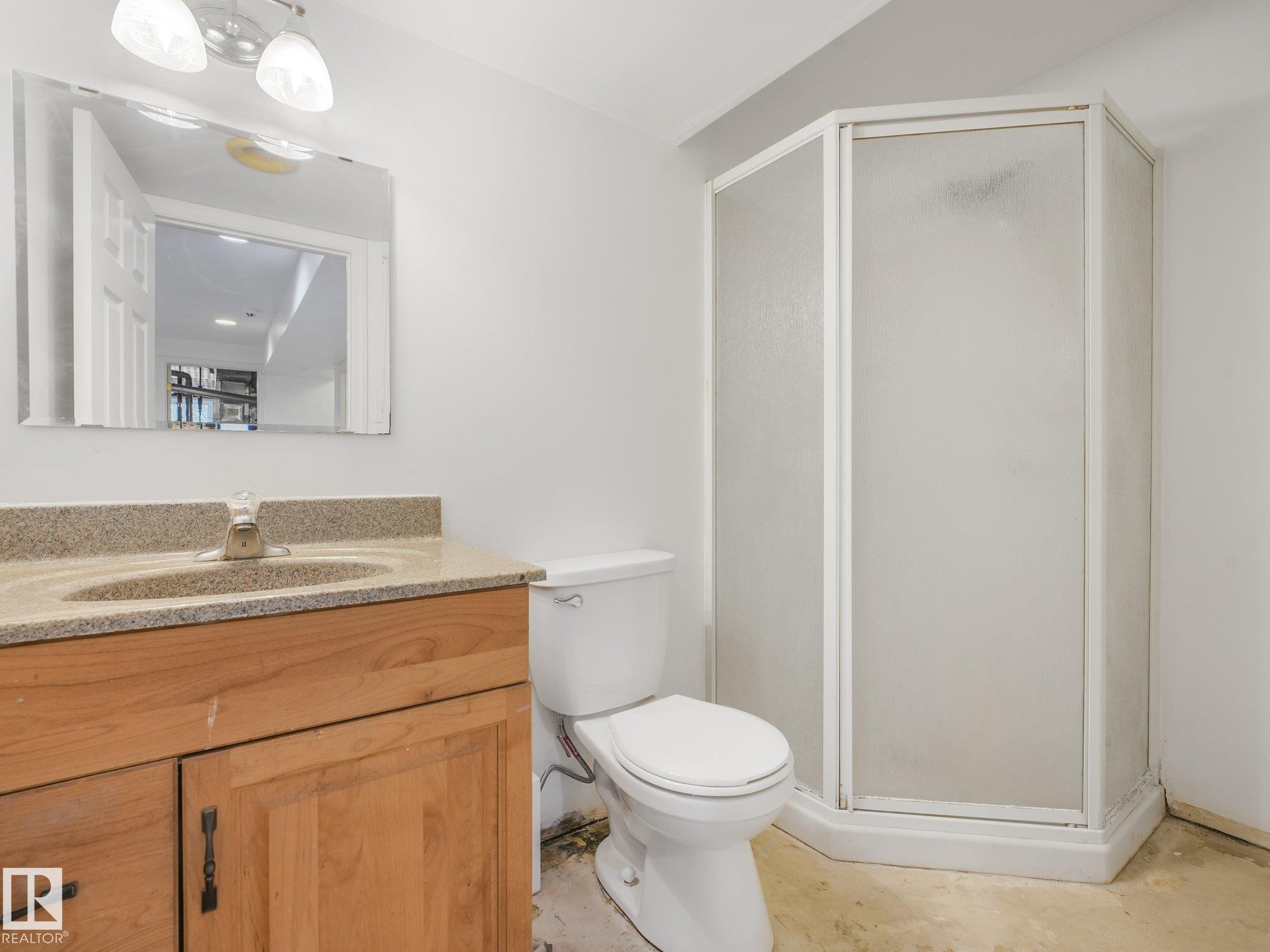 Wood-finish vanity with an integrated sink, polished chrome faucet, and a wall-mounted mirror - 16428 88 Avenue Nw, Edmonton, AB