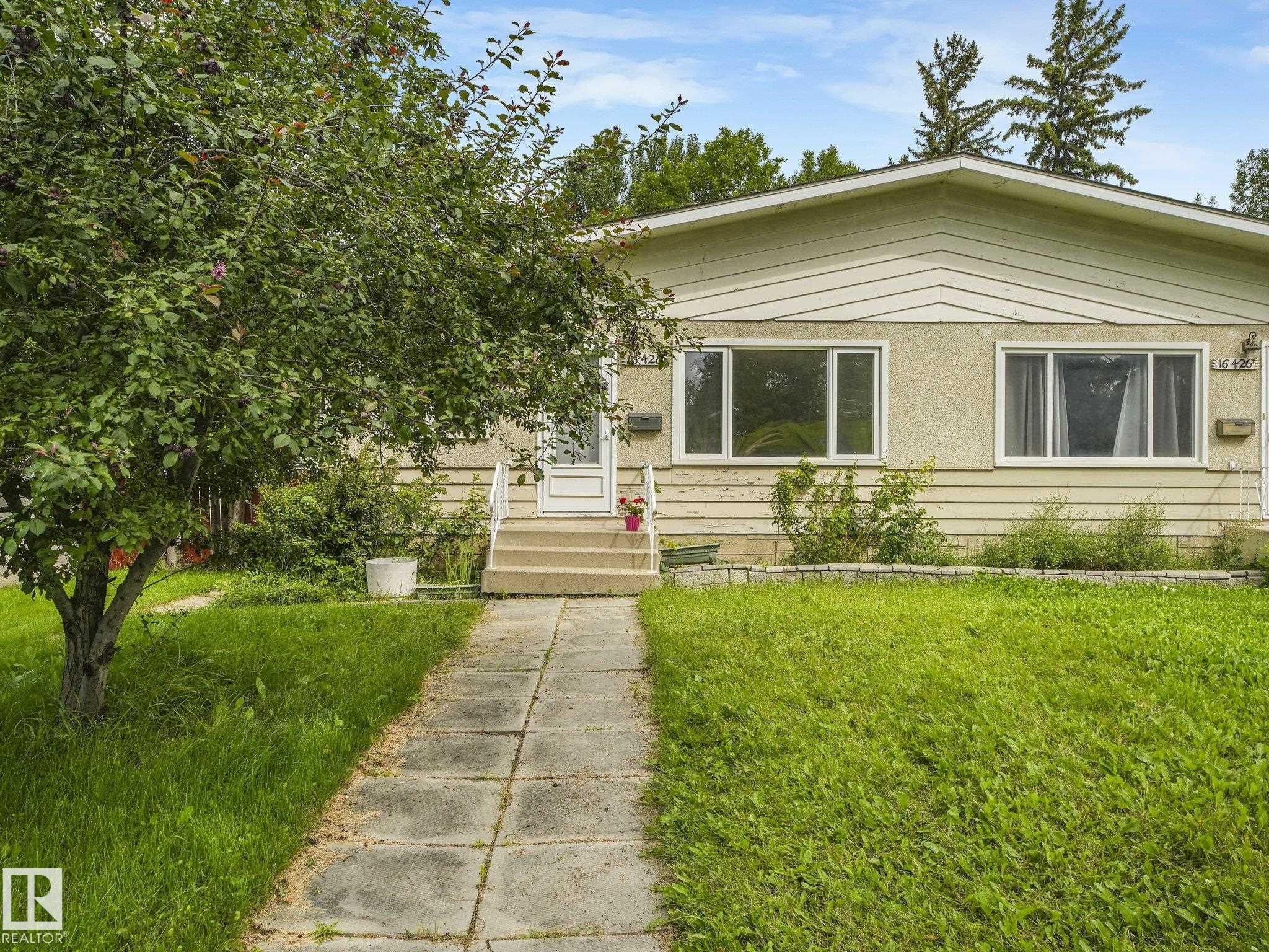 Front facade with two large windows, a raised entry, and a mature tree - 16428 88 Avenue Nw, Edmonton, AB