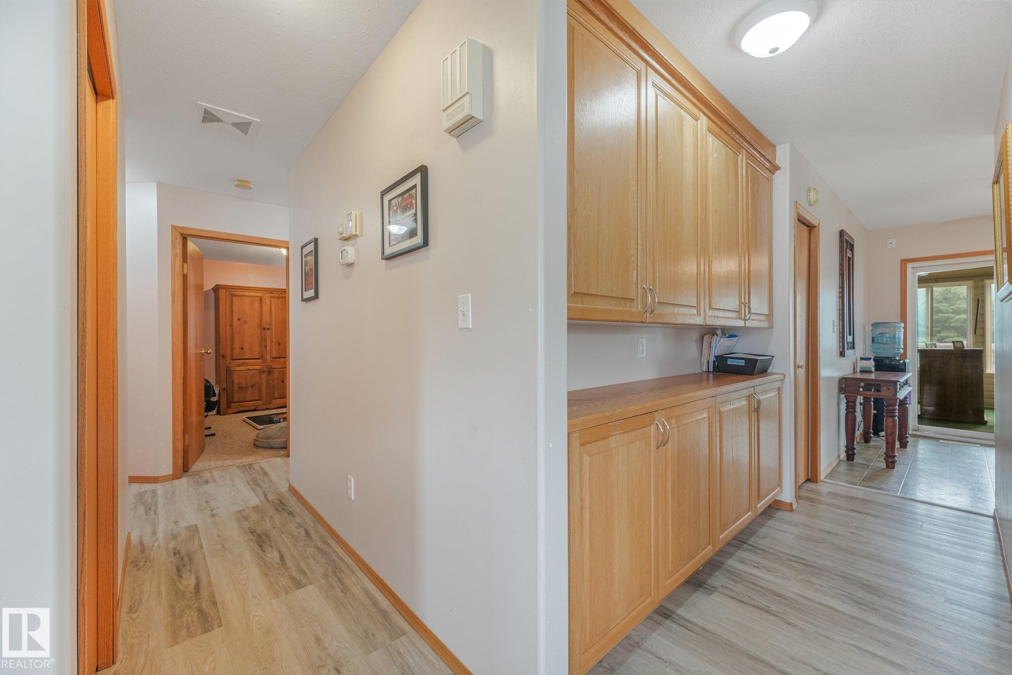Hallway with built-in wood cabinetry and wood-finish flooring - 54 Buskmose Dr, Rural Wetaskiwin County, AB - Indoor Photo Showing Other Room