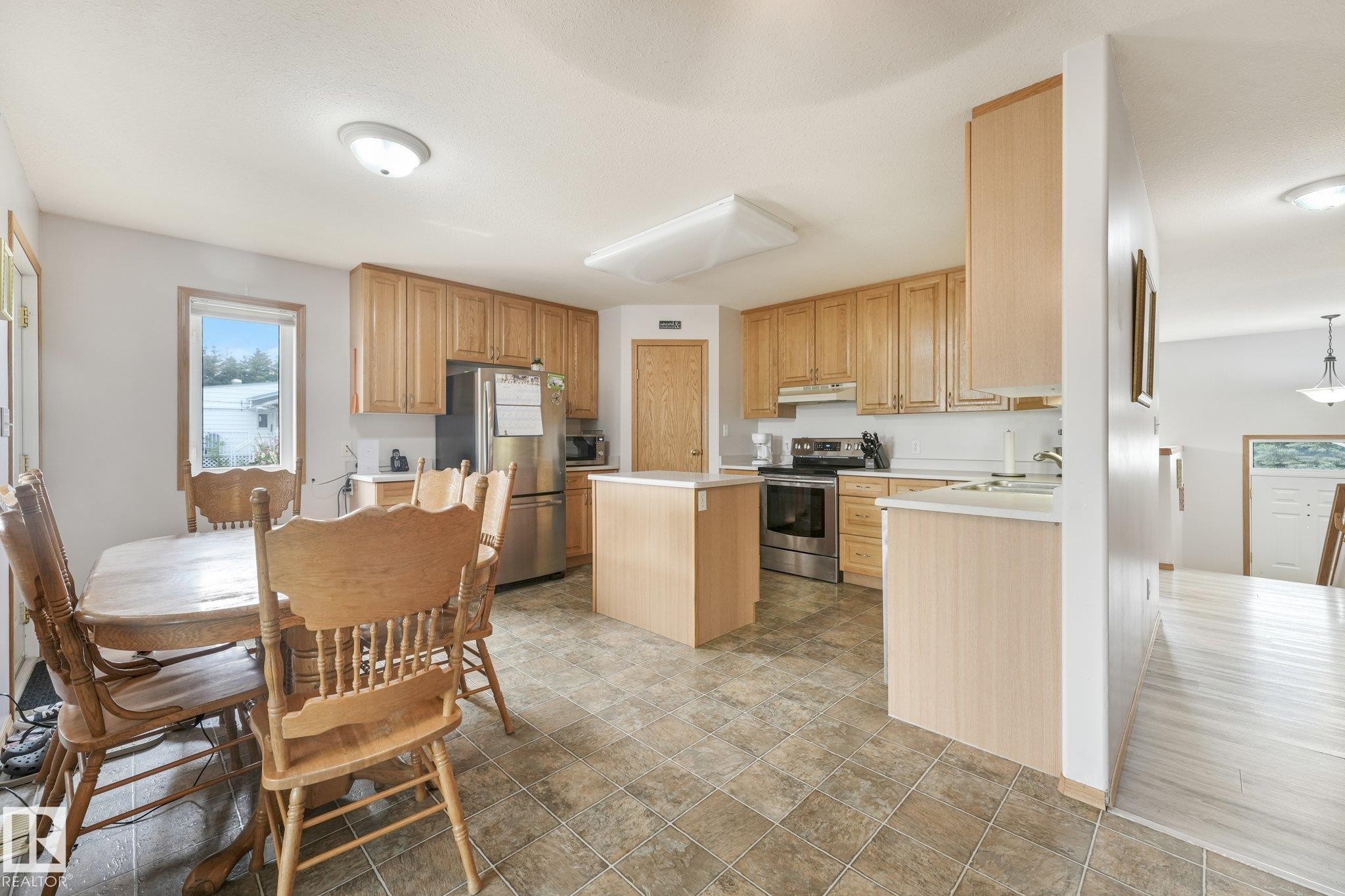 Kitchen featuring light wood cabinetry, stainless steel appliances, and a central island - 54 Buskmose Dr, Rural Wetaskiwin County, AB - Indoor