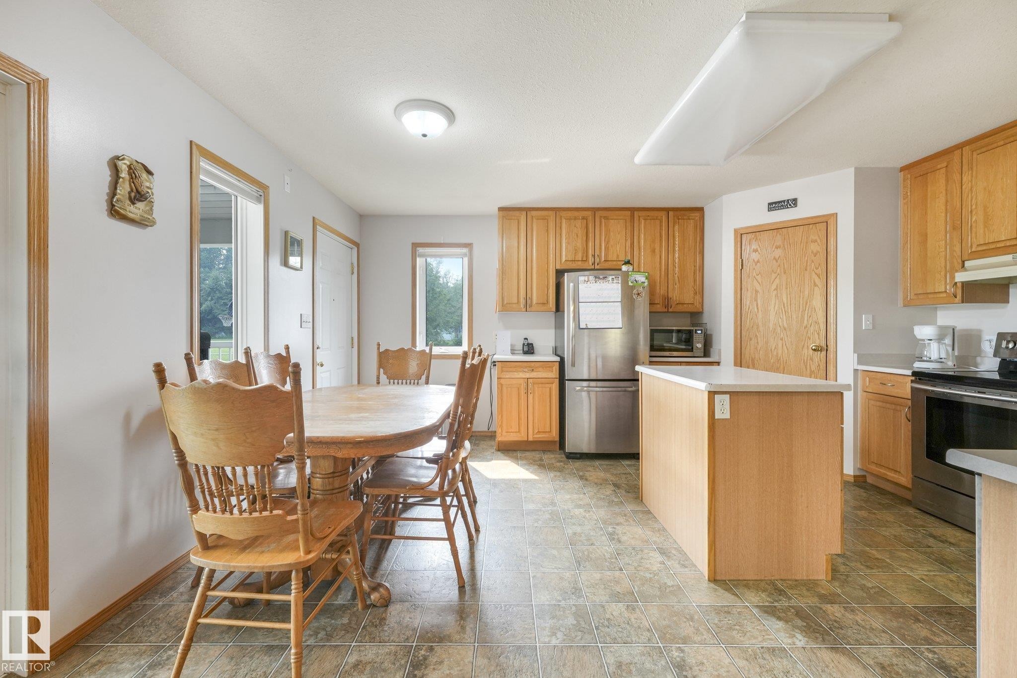 Open concept kitchen featuring light wood cabinetry, stainless steel appliances, a central island with a light-toned countertop, and tile flooring - 54 Buskmose Dr, Rural Wetaskiwin County, AB - Indoor