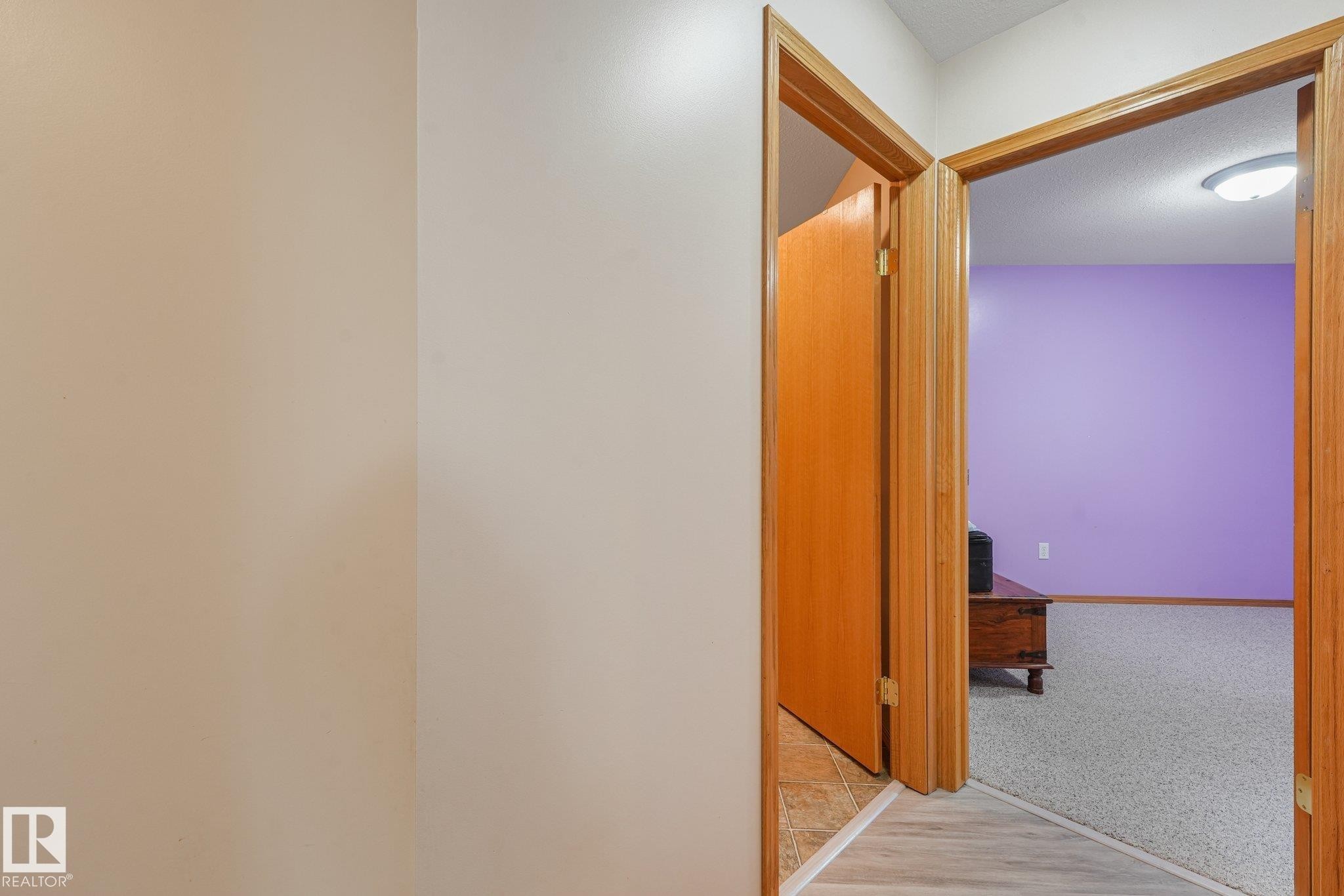 Interior hallway with light wood-finish flooring transitioning to light grey carpet - 54 Buskmose Dr, Rural Wetaskiwin County, AB - Indoor Photo Showing Other Room