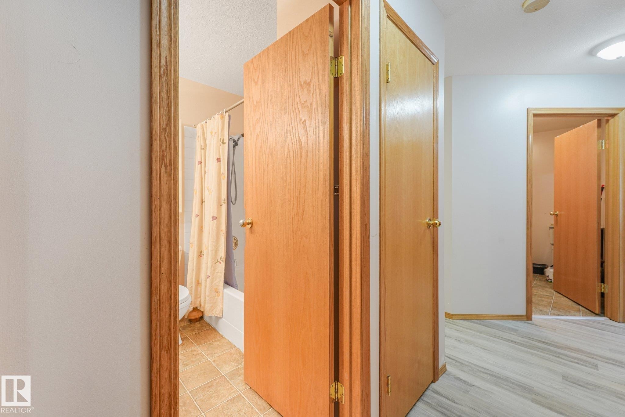 Hallway featuring wood-finish doors, light wood-finish flooring, and a ceiling-mounted light fixture - 54 Buskmose Dr, Rural Wetaskiwin County, AB - Indoor Photo Showing Other Room