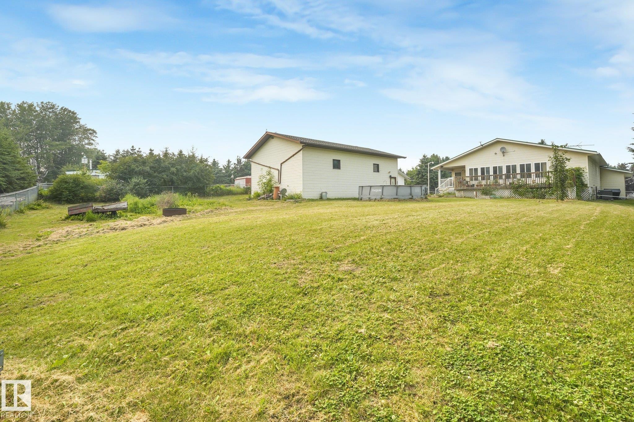 Expansive grassy yard with two detached structures - 54 Buskmose Dr, Rural Wetaskiwin County, AB - Outdoor With Deck Patio Veranda With Exterior