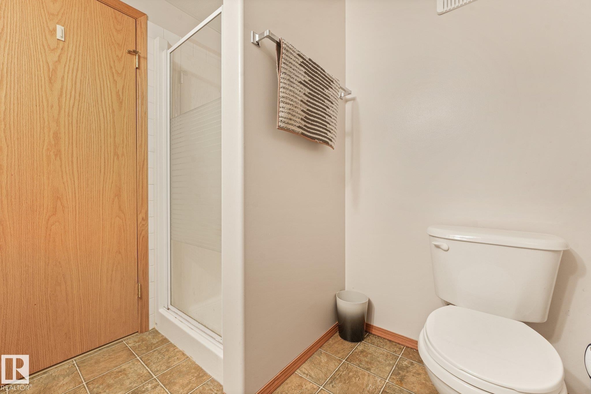 Bathroom featuring tile flooring, a glass-enclosed shower, and a white toilet - 54 Buskmose Dr, Rural Wetaskiwin County, AB - Indoor Photo Showing Bathroom