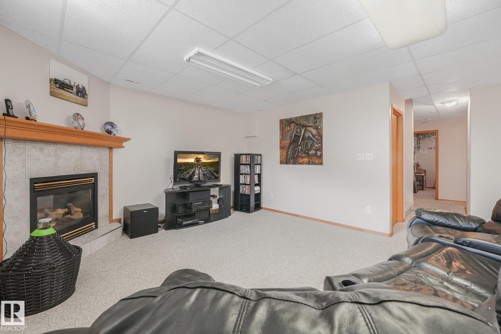 Carpeted interior space featuring a fireplace with a tile surround and wood mantel - 54 Buskmose Dr, Rural Wetaskiwin County, AB - Indoor Photo Showing Living Room With Fireplace