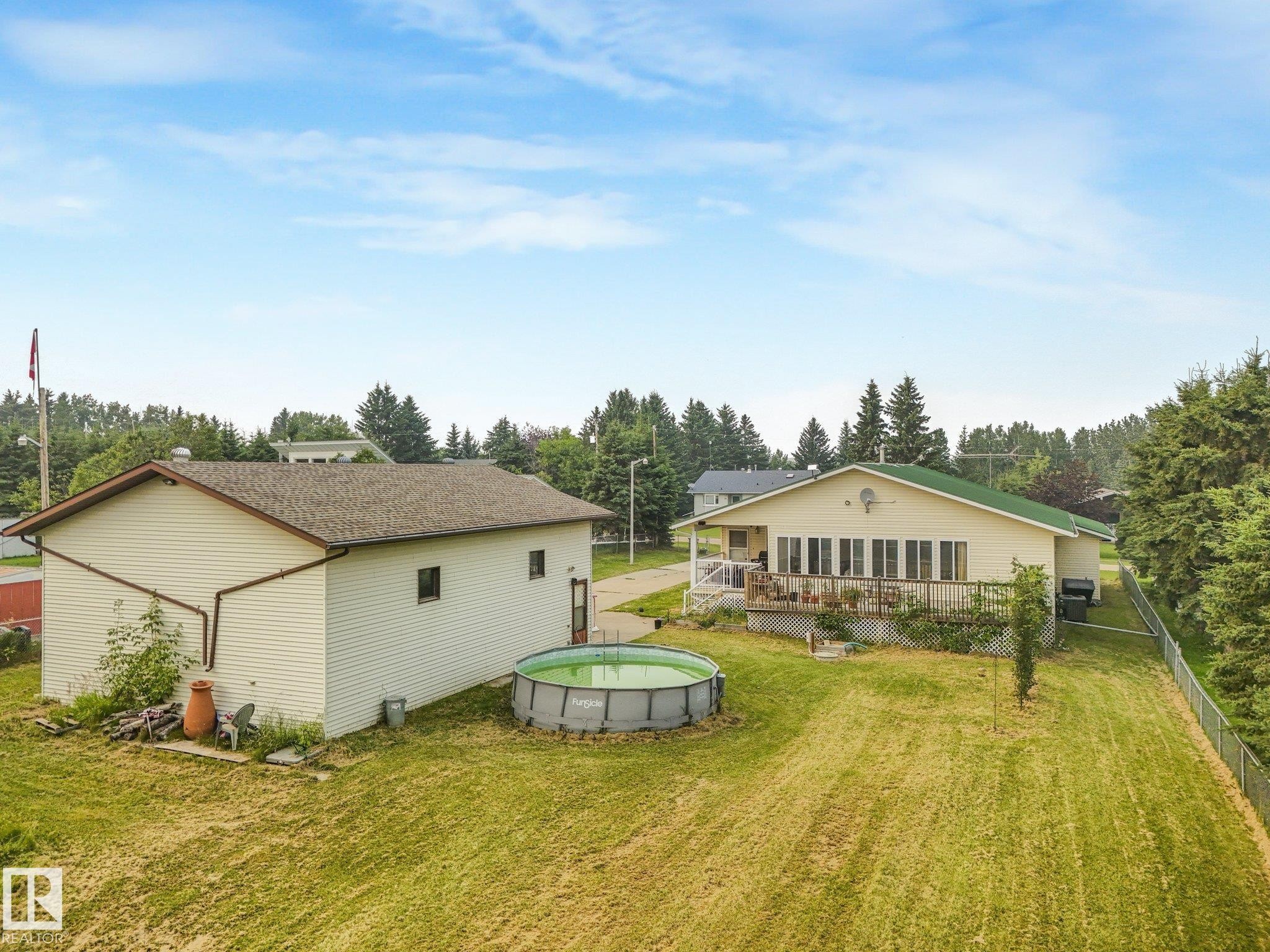 Expansive backyard featuring a large accessory building, above-ground pool, and a chain-link fence - 54 Buskmose Dr, Rural Wetaskiwin County, AB - Outdoor With Exterior