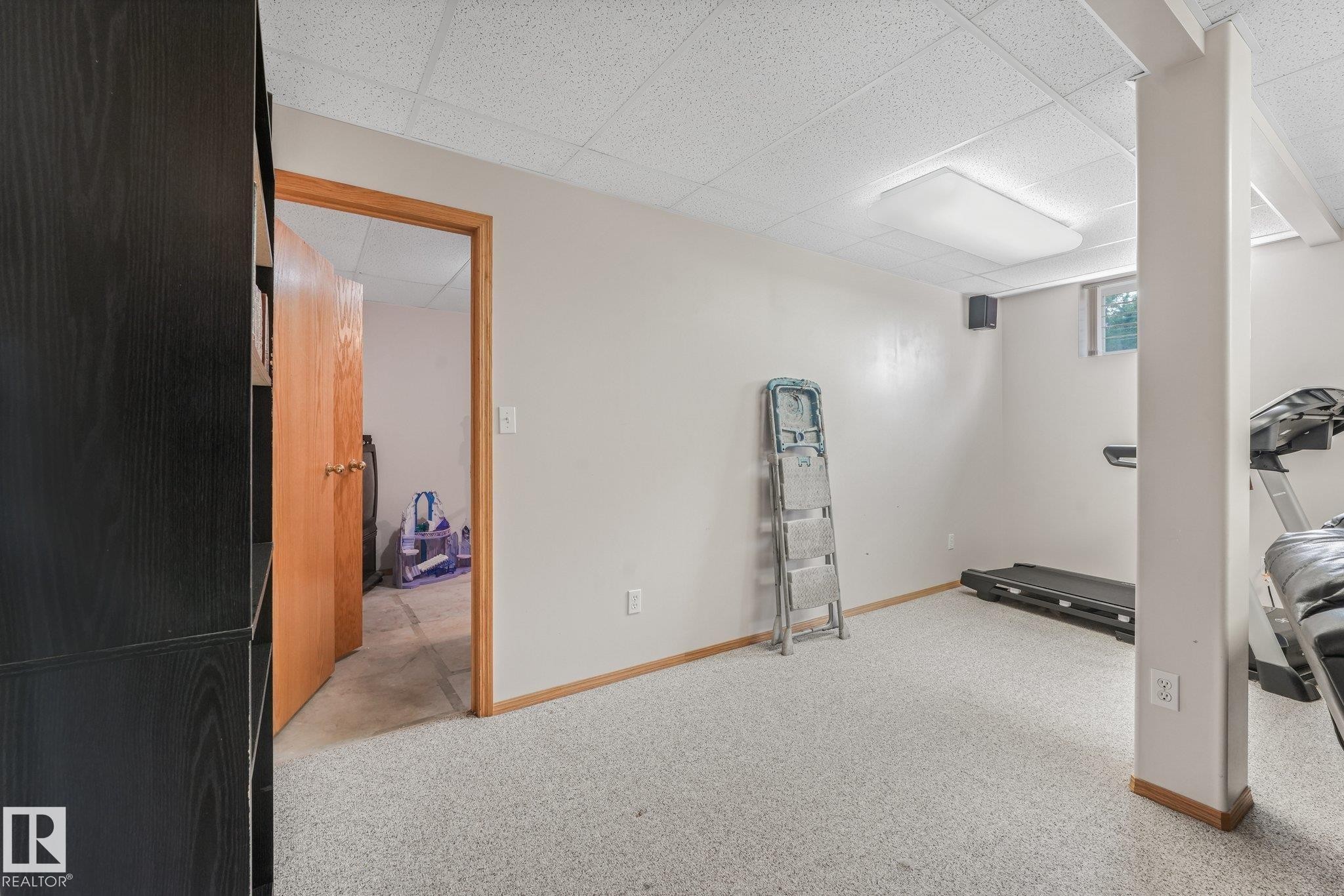 Finished room featuring light-colored carpeting, a drop ceiling with recessed lighting, and a window providing natural illumination - 54 Buskmose Dr, Rural Wetaskiwin County, AB - Indoor