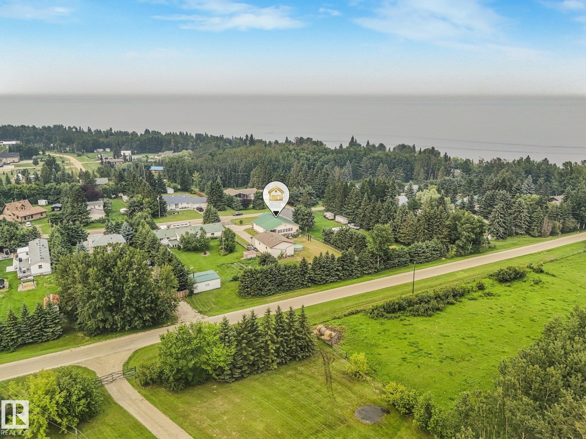 Expansive property featuring a green-roofed structure, mature trees, and a paved roadway - 54 Buskmose Dr, Rural Wetaskiwin County, AB - Outdoor With View