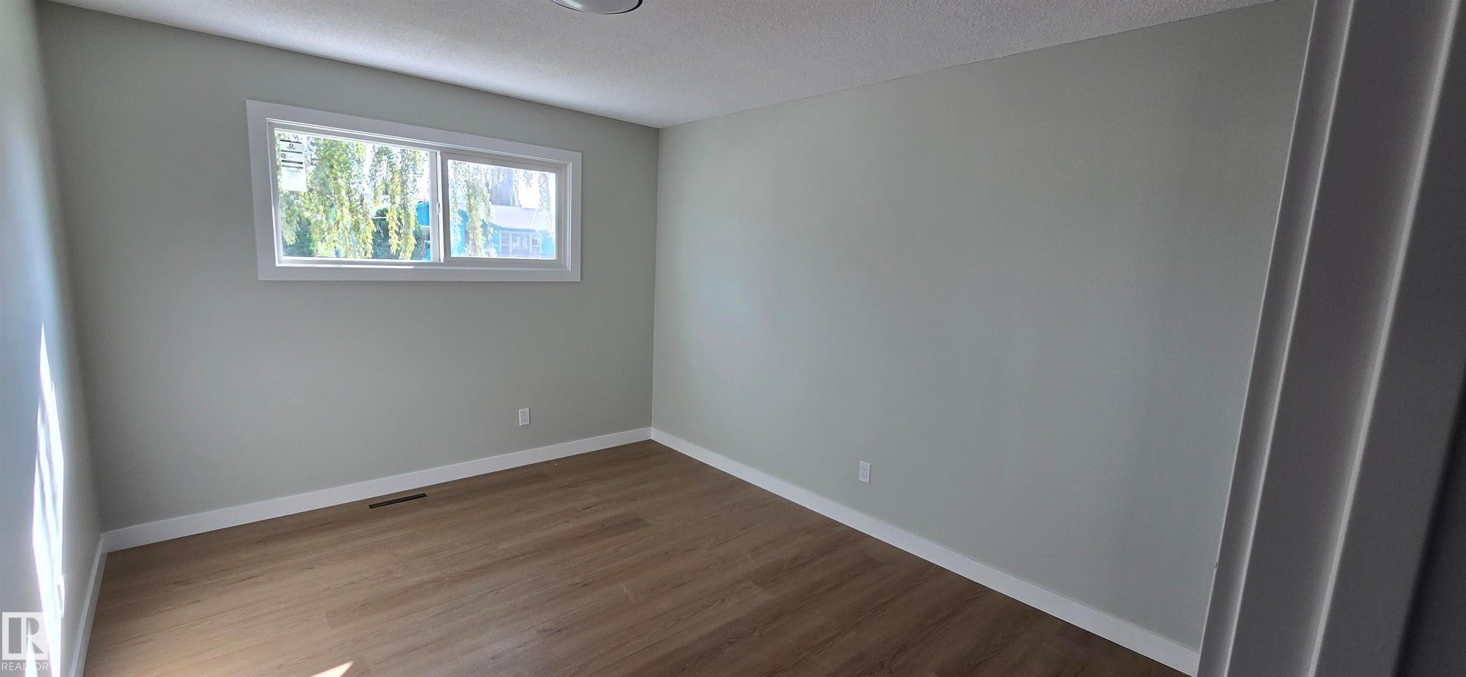 Wood-finish flooring, light grey wall paint, and a white-framed window - 13812 63 Street Nw, Edmonton, AB