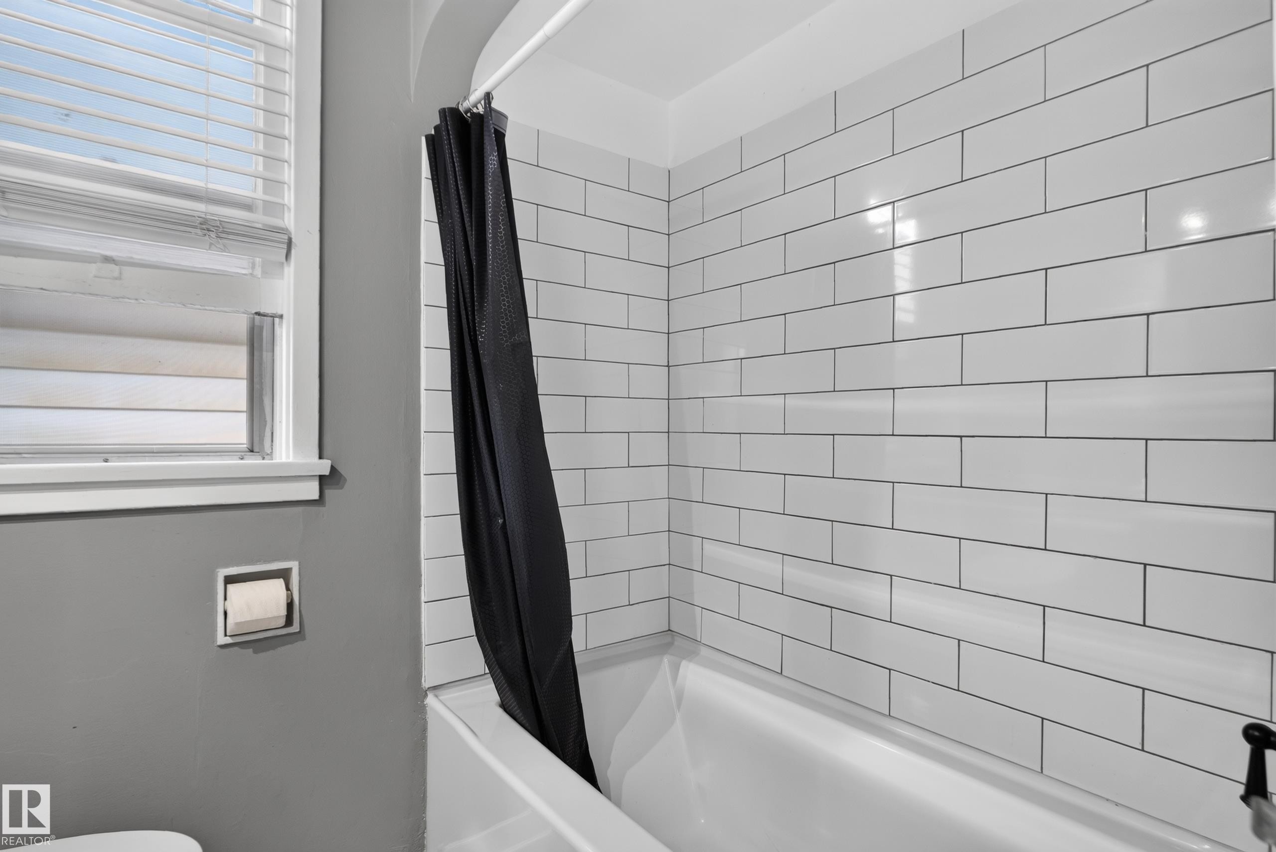 Built-in tub with white subway tile surround and a window with blinds - 11406 83 Street Nw, Edmonton, AB