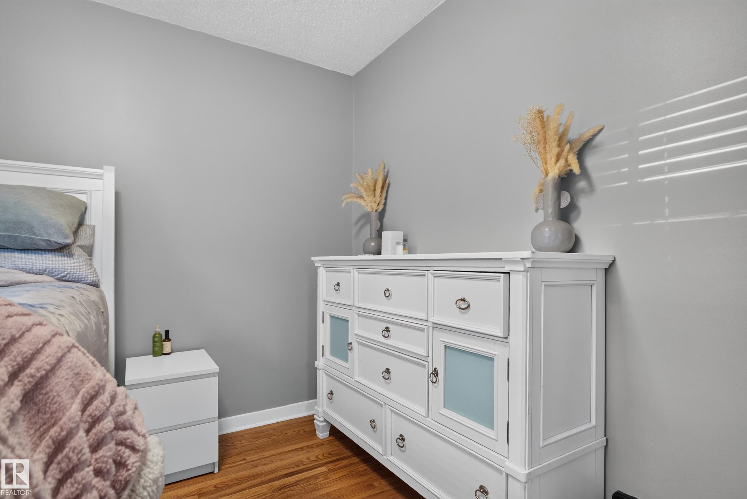 Wood-finish flooring with white baseboards and neutral wall tones - 11406 83 Street Nw, Edmonton, AB