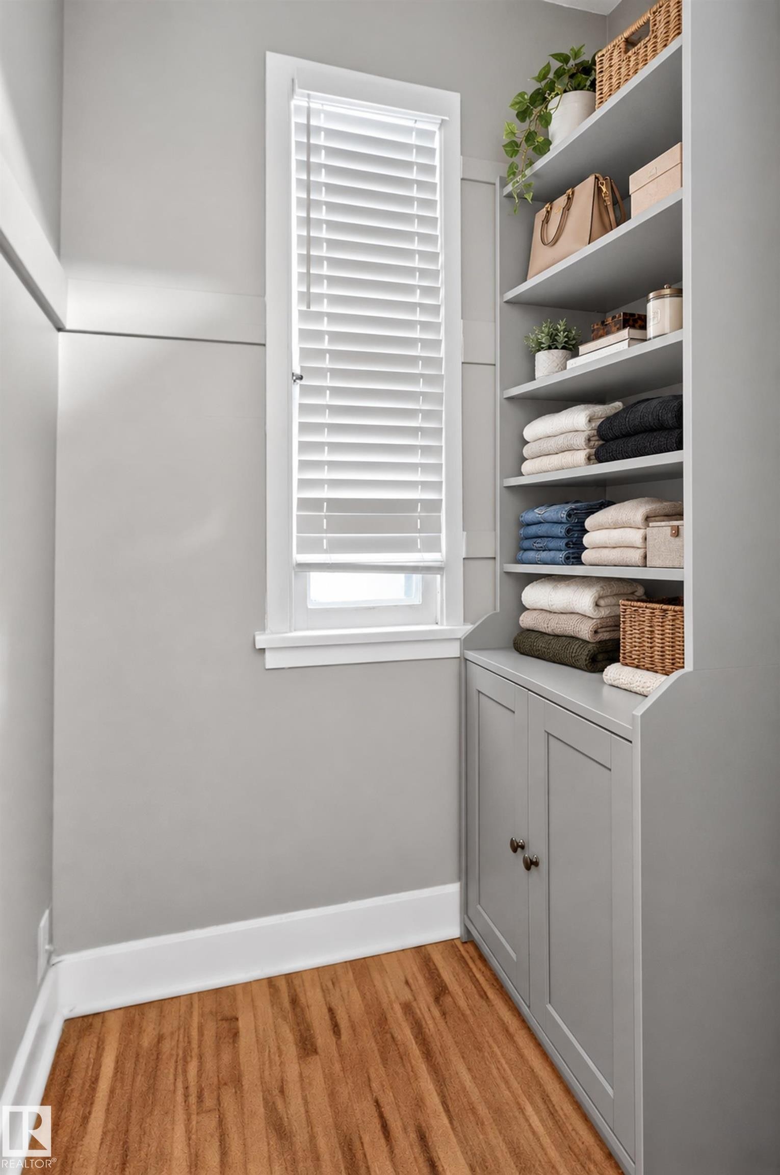Built-in shelving unit with lower cabinetry, wood-finish flooring, and natural light from a window with blinds - 11406 83 Street Nw, Edmonton, AB