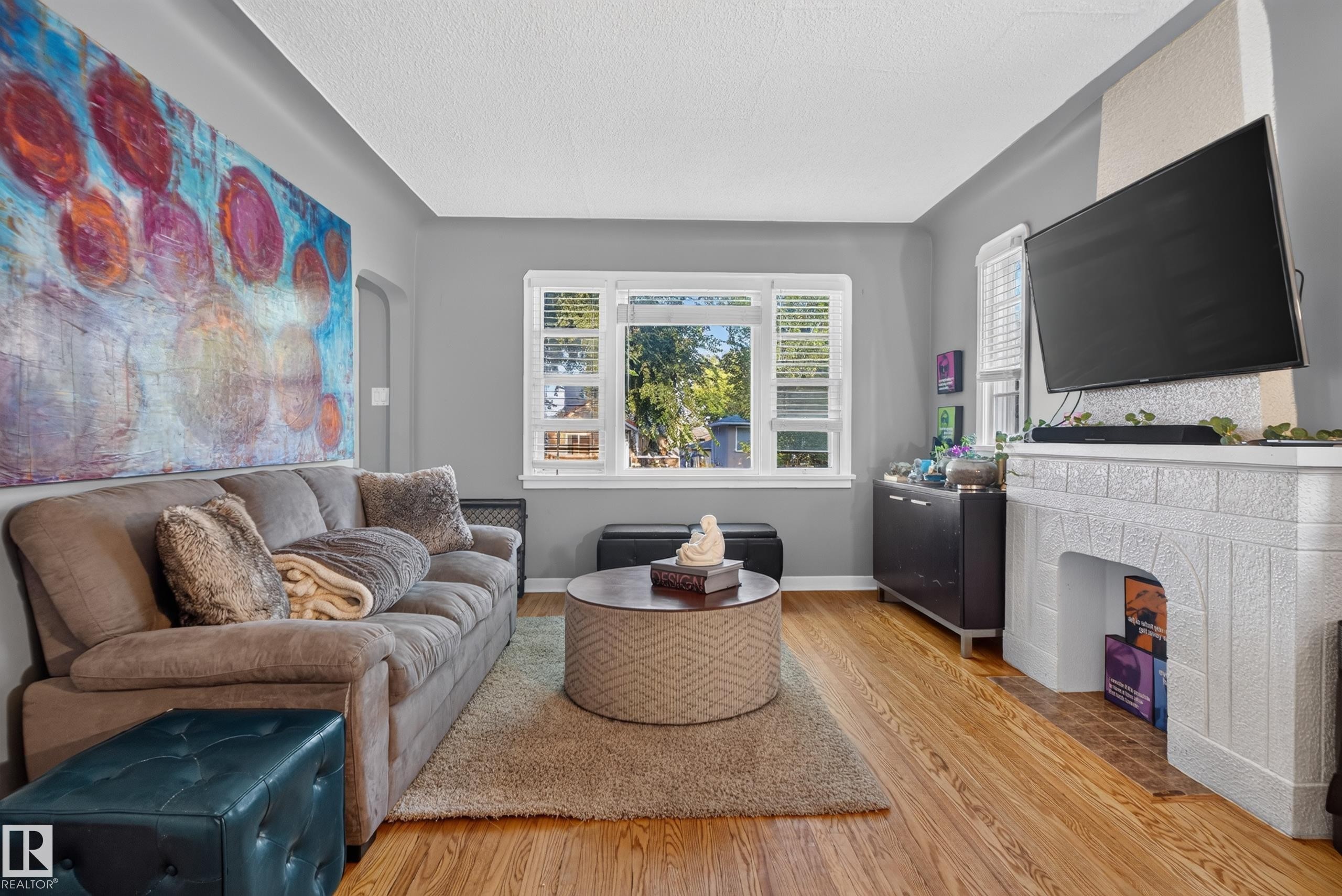 Hardwood flooring, painted walls, window with blinds, built-in fireplace, and overhead lighting - 11406 83 Street Nw, Edmonton, AB