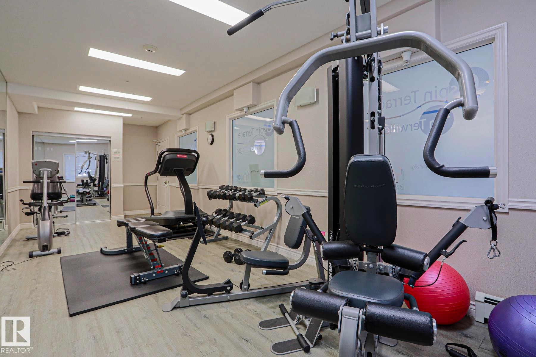 Fitness center featuring multiple exercise machines, weight training equipment, and wood-finish flooring - #108 1204 156 St Nw, Edmonton, AB