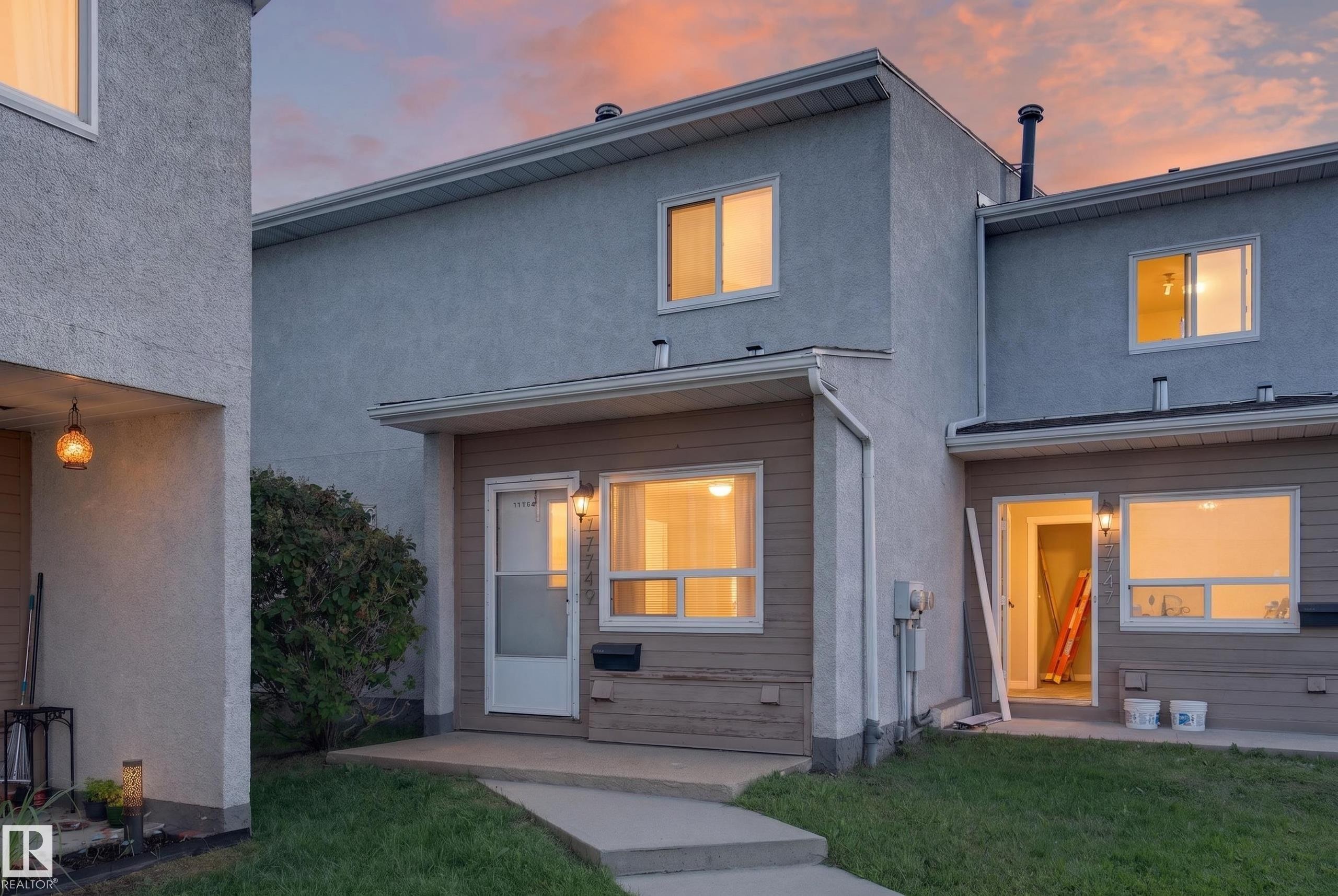 Multi-story townhouse exterior featuring a stucco and siding facade, white window frames, and a concrete walkway - 17749 95 Street Nw, Edmonton, AB