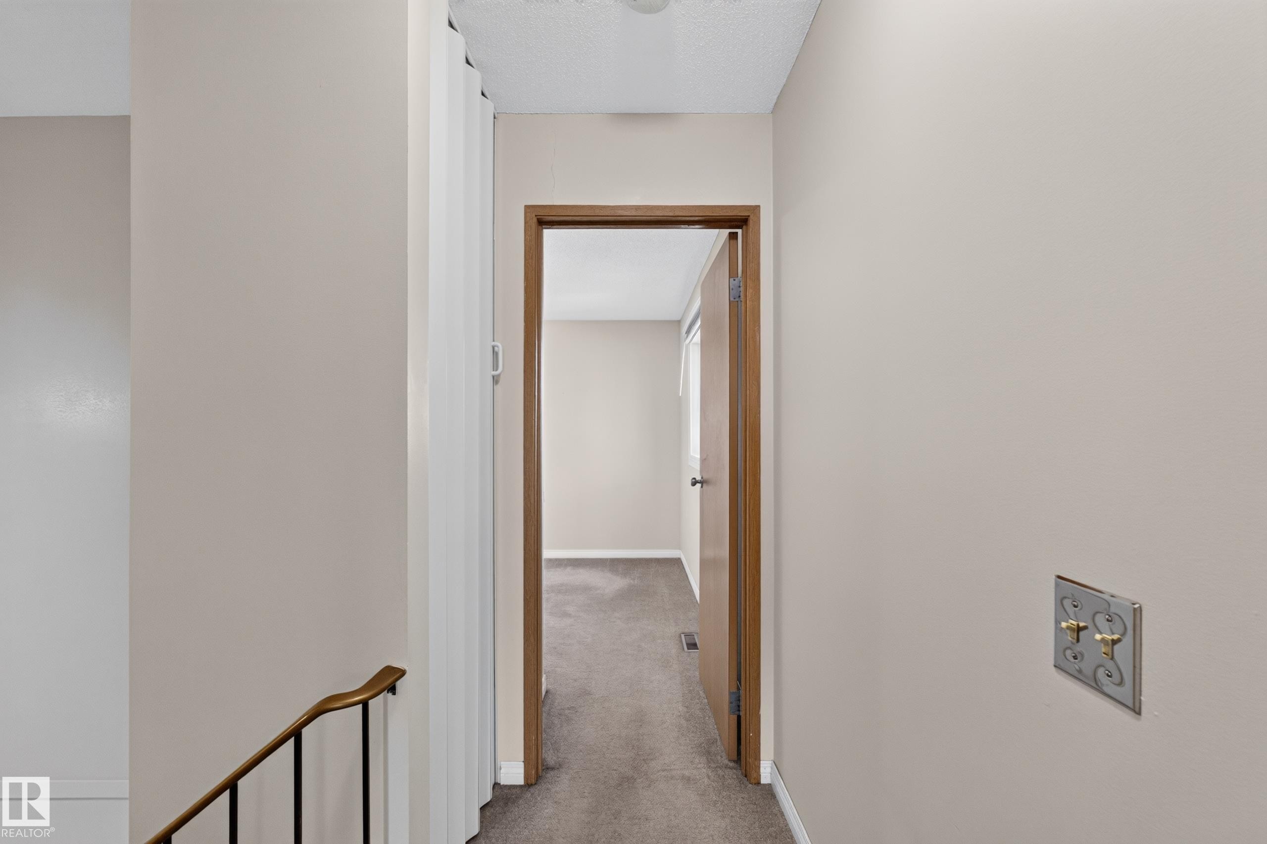 Hallway with neutral wall paint, wood-finish door frames, and textured ceiling - 17749 95 Street Nw, Edmonton, AB