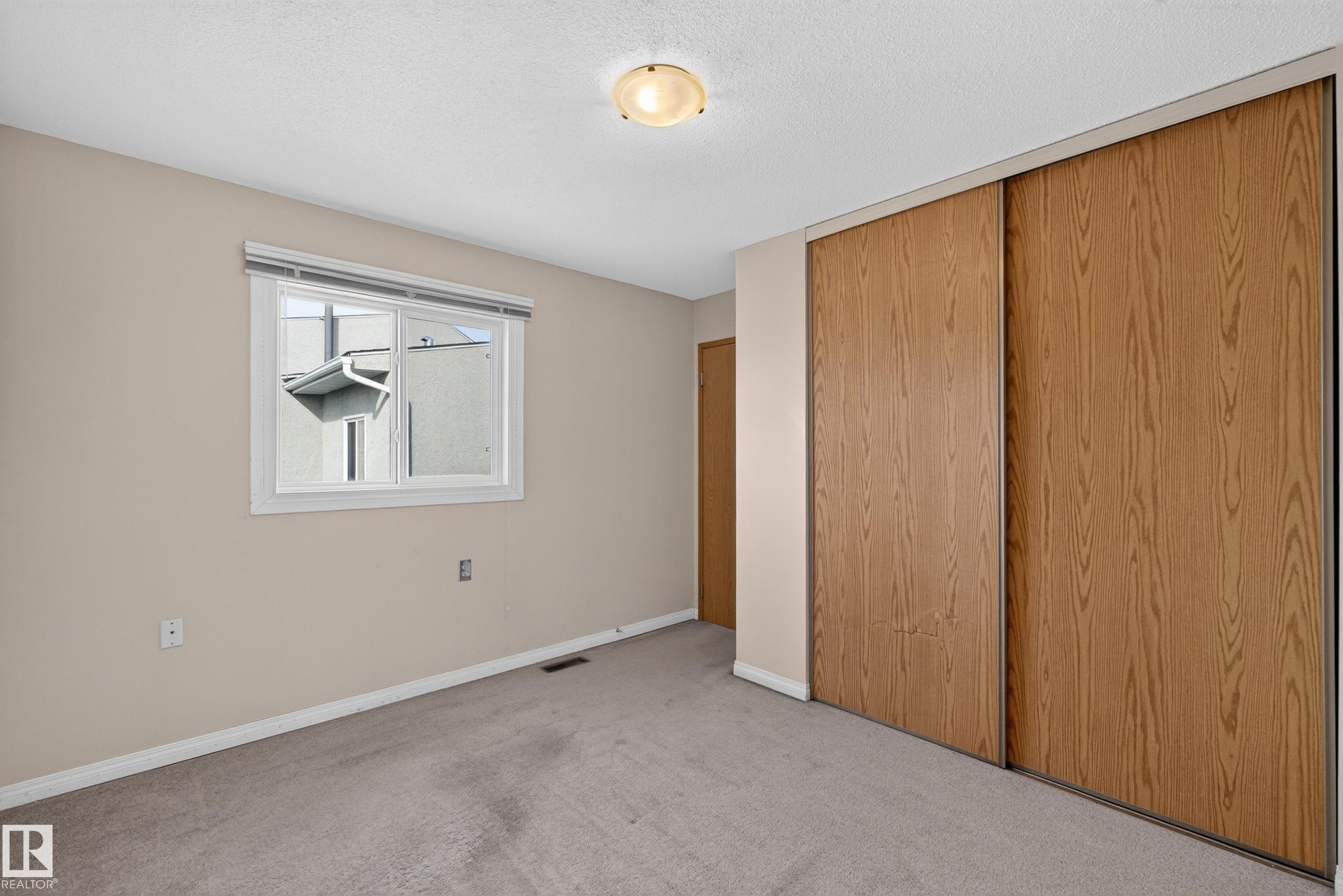 Neutral wall color, carpet flooring, window with blinds, wood-finish sliding doors, and ceiling-mounted light fixture - 17749 95 Street Nw, Edmonton, AB
