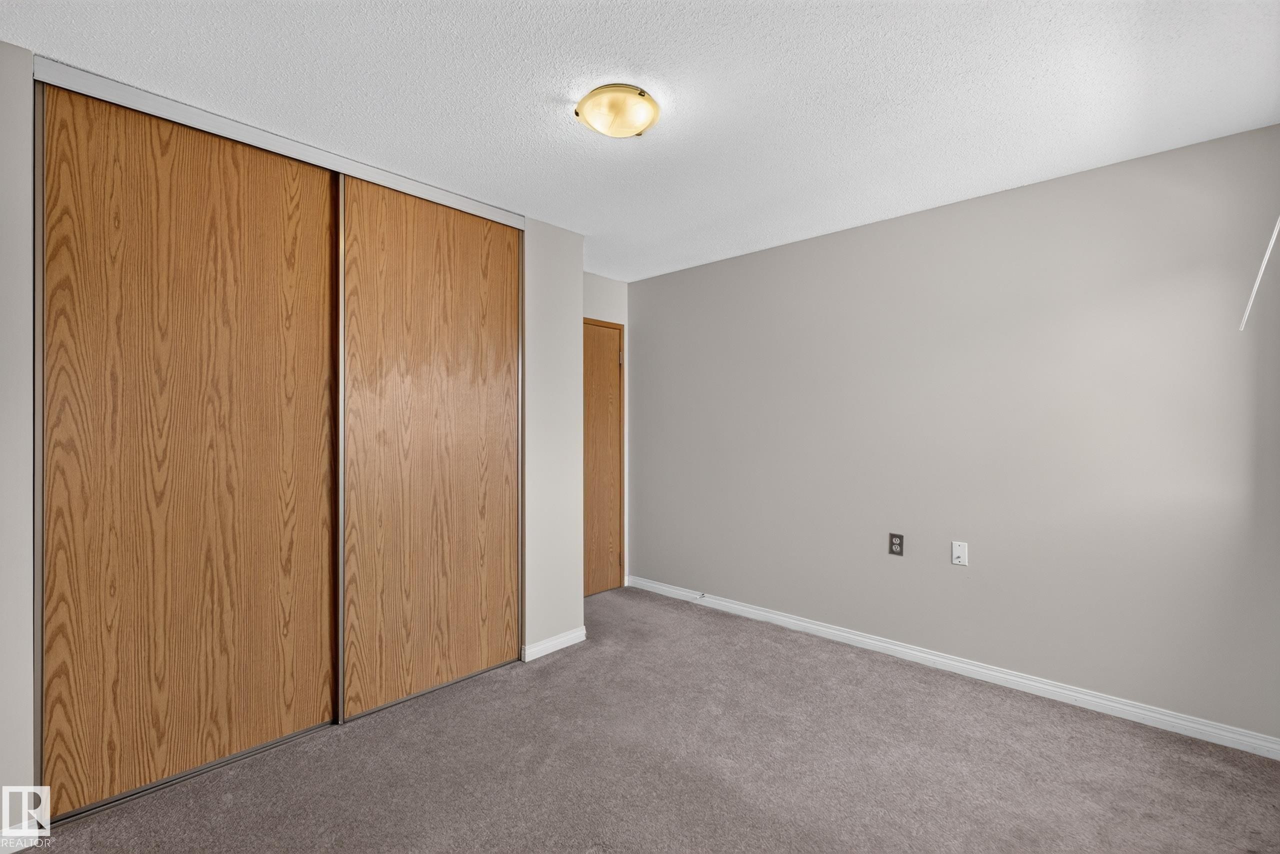 Wood-finish sliding closet doors, wall-to-wall carpeting, light neutral wall paint, and a flush mount ceiling light - 17749 95 Street Nw, Edmonton, AB