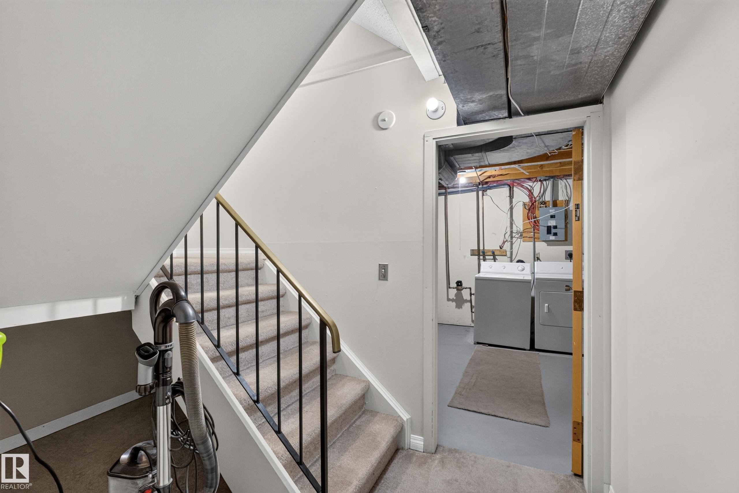 Carpeted staircase with black metal balusters and a brass-tone handrail - 17749 95 Street Nw, Edmonton, AB