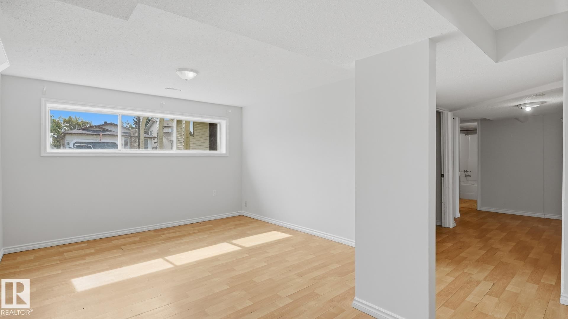 Light wood-finish flooring, white walls, and a multi-pane horizontal window - 12208 146 Avenue Nw, Edmonton, AB