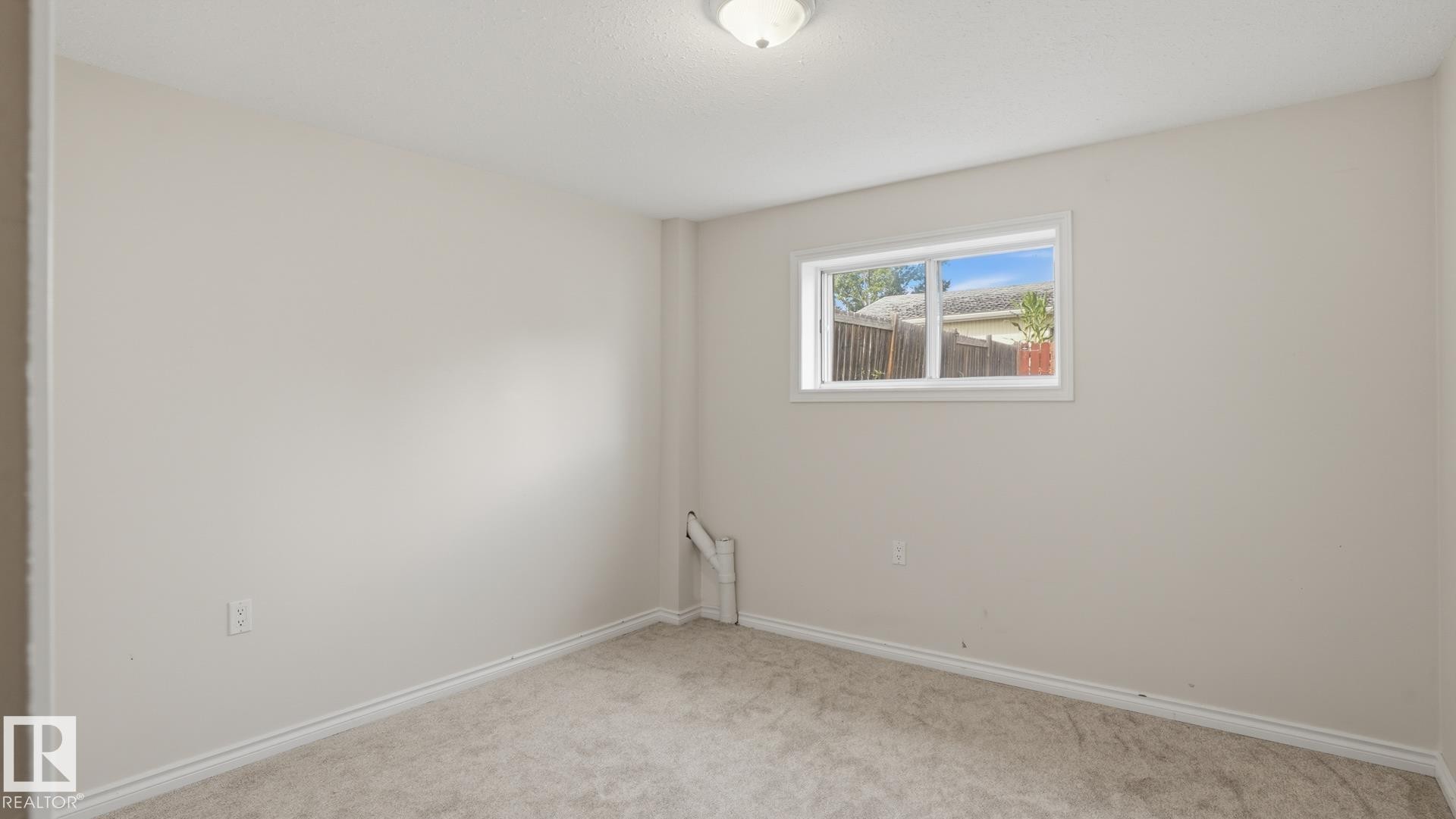 Neutral-toned walls, light-colored carpeting, a single window, and a ceiling-mounted light fixture - 12208 146 Avenue Nw, Edmonton, AB