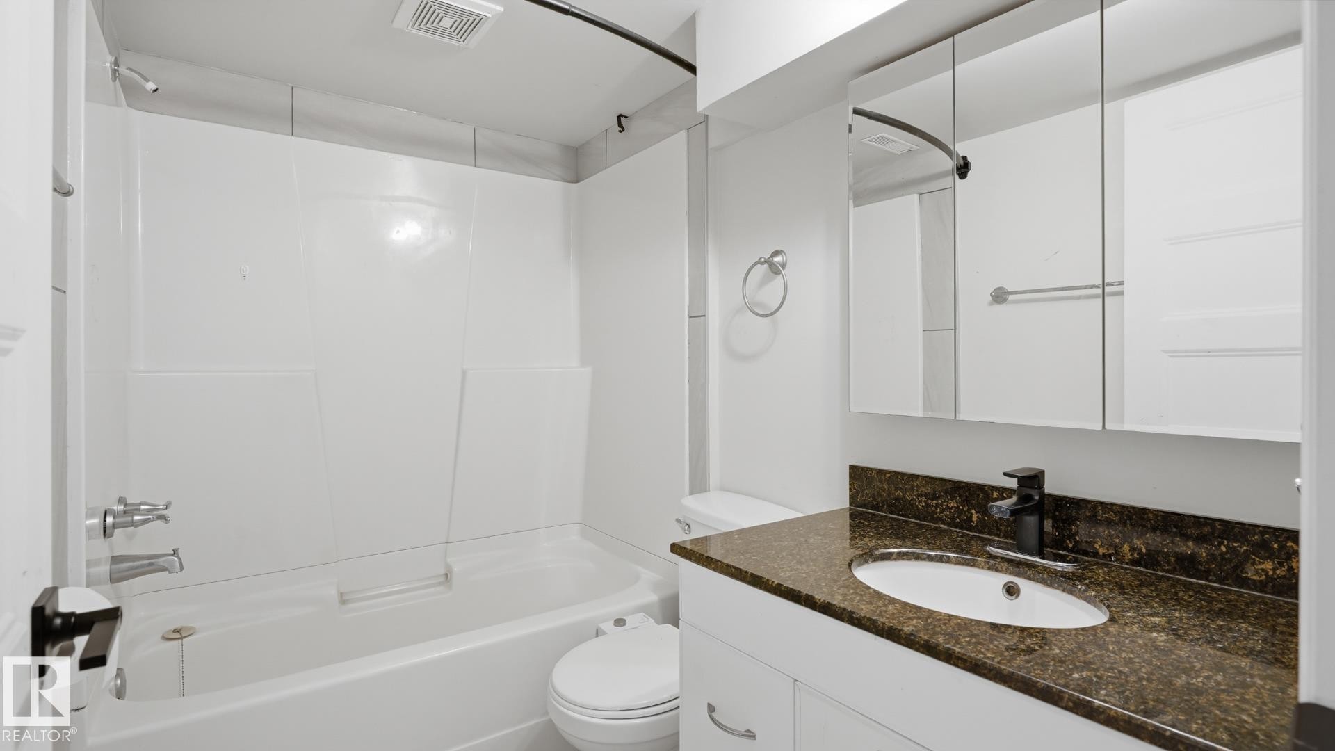 Tub-shower combination with white surround, vanity with granite-finish countertop, undermount sink, black-finish faucet, and mirrored medicine cabinet - 12208 146 Avenue Nw, Edmonton, AB