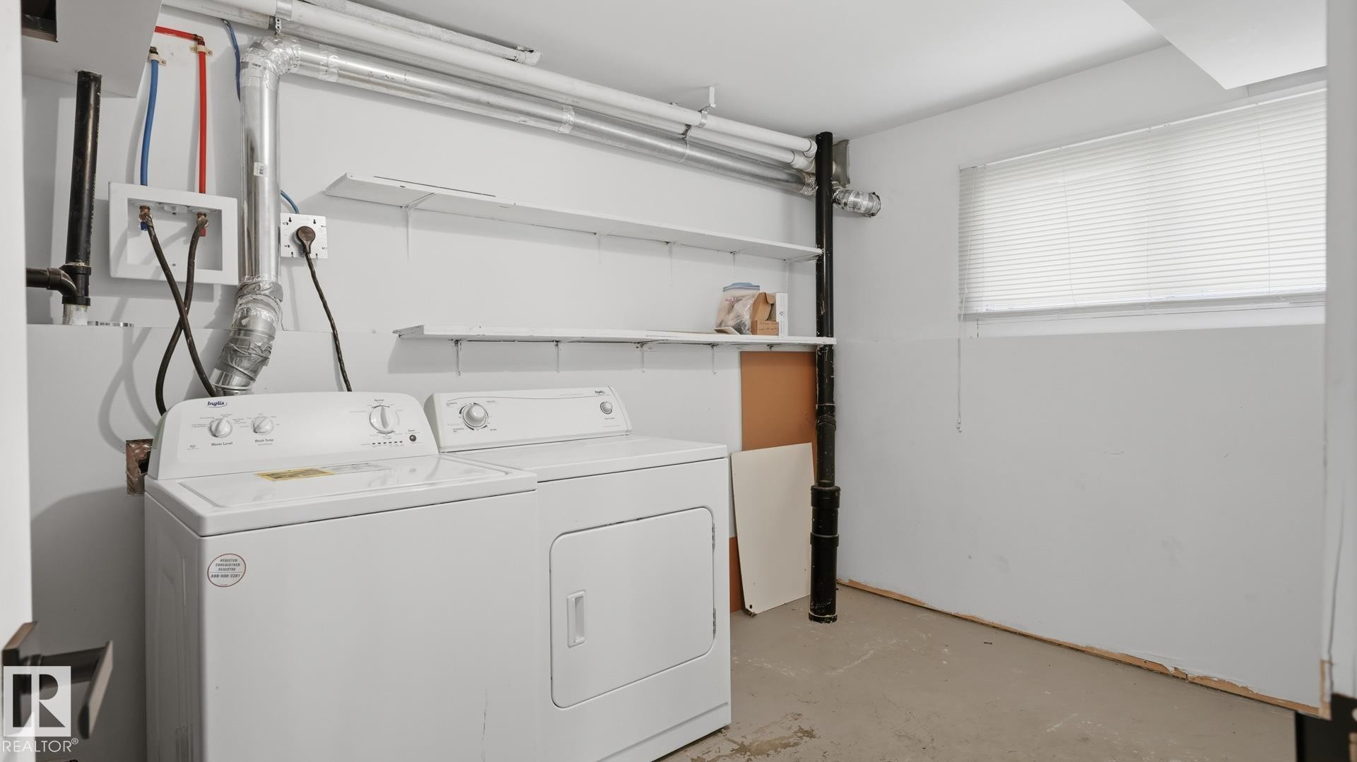 Dedicated laundry area with a washer and dryer, fixed utility shelving, and a window with blinds - 12208 146 Avenue Nw, Edmonton, AB