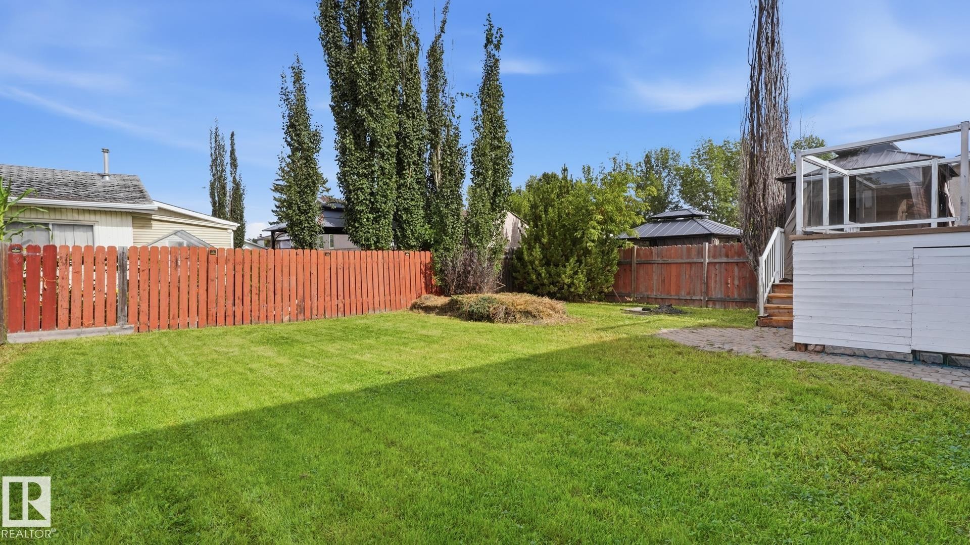 Expansive backyard featuring a lush lawn, privacy fencing, and a multi-level deck with a gazebo - 12208 146 Avenue Nw, Edmonton, AB