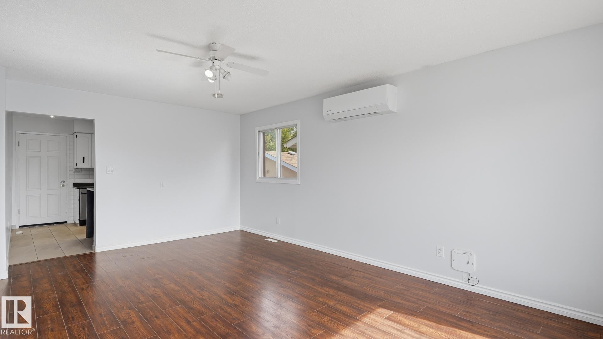 Wood-finish flooring, ceiling fan with integrated lighting, wall-mounted air conditioning unit, and white baseboards - 12208 146 Avenue Nw, Edmonton, AB