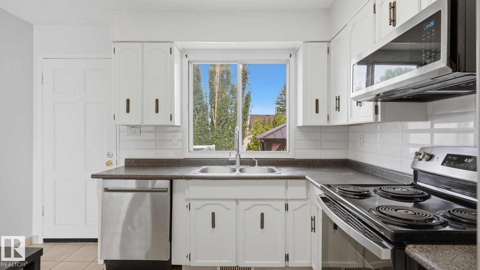 White cabinetry with dark hardware, a double basin sink, and a stainless steel dishwasher - 12208 146 Avenue Nw, Edmonton, AB