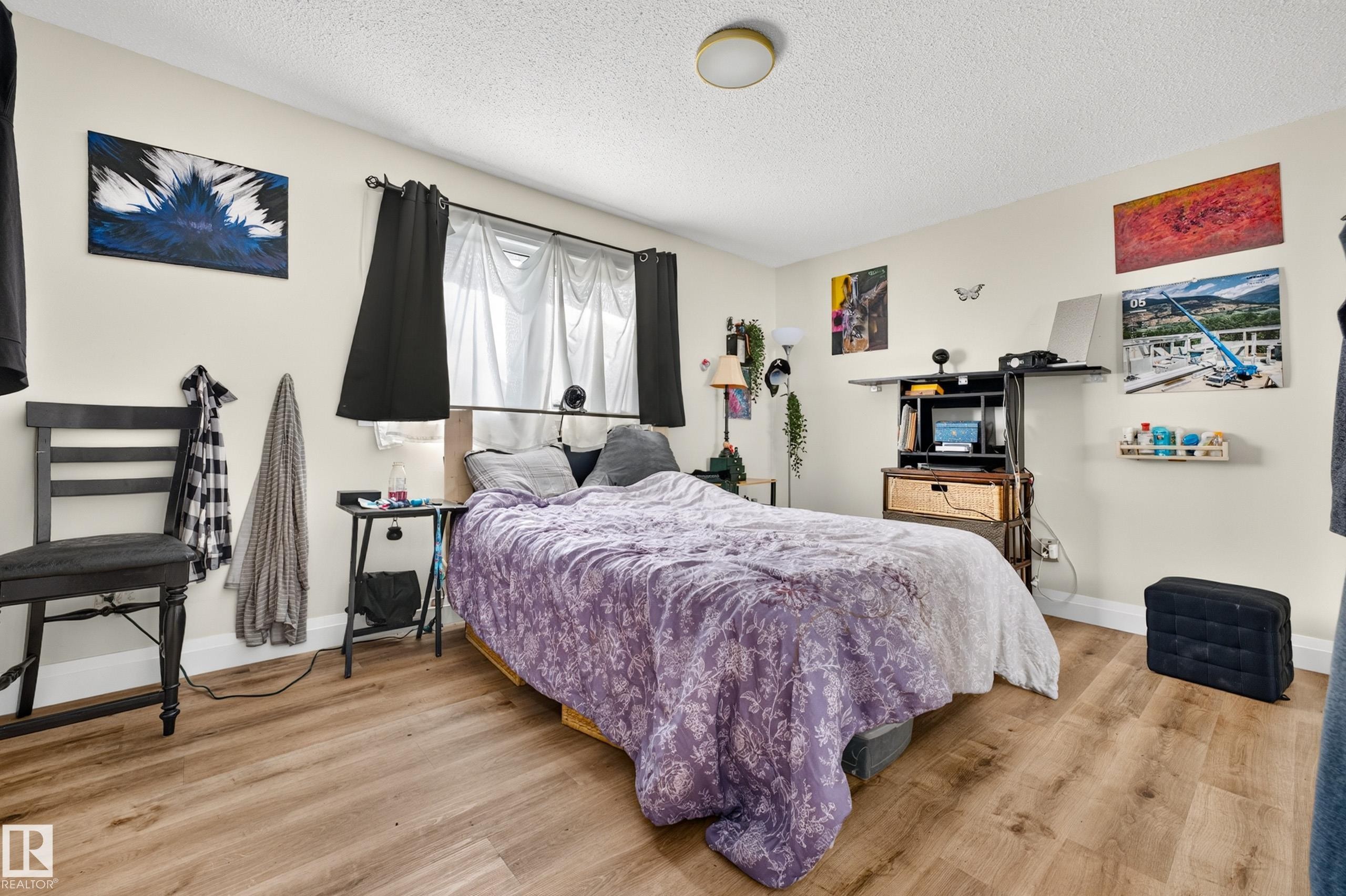 Recessed window with dark curtain rods, light-toned walls, and wood-finish flooring - 2412 80 Street Nw, Edmonton, AB