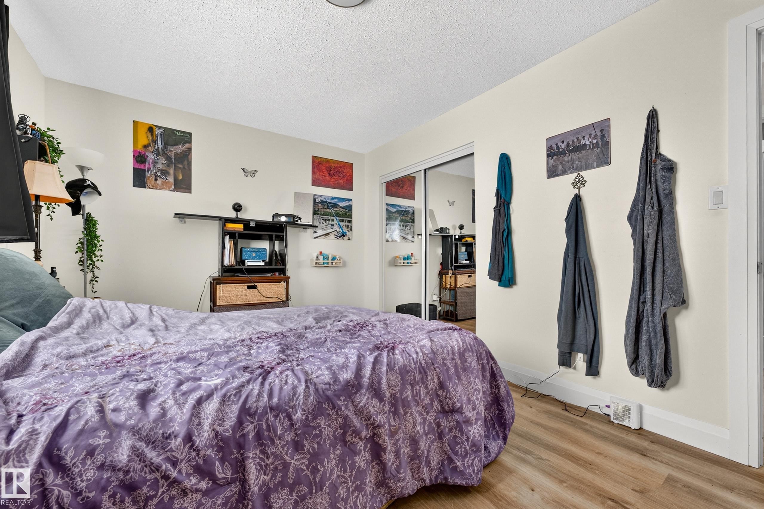 Wood-finish flooring with white baseboards, and a sliding mirrored closet door - 2412 80 Street Nw, Edmonton, AB