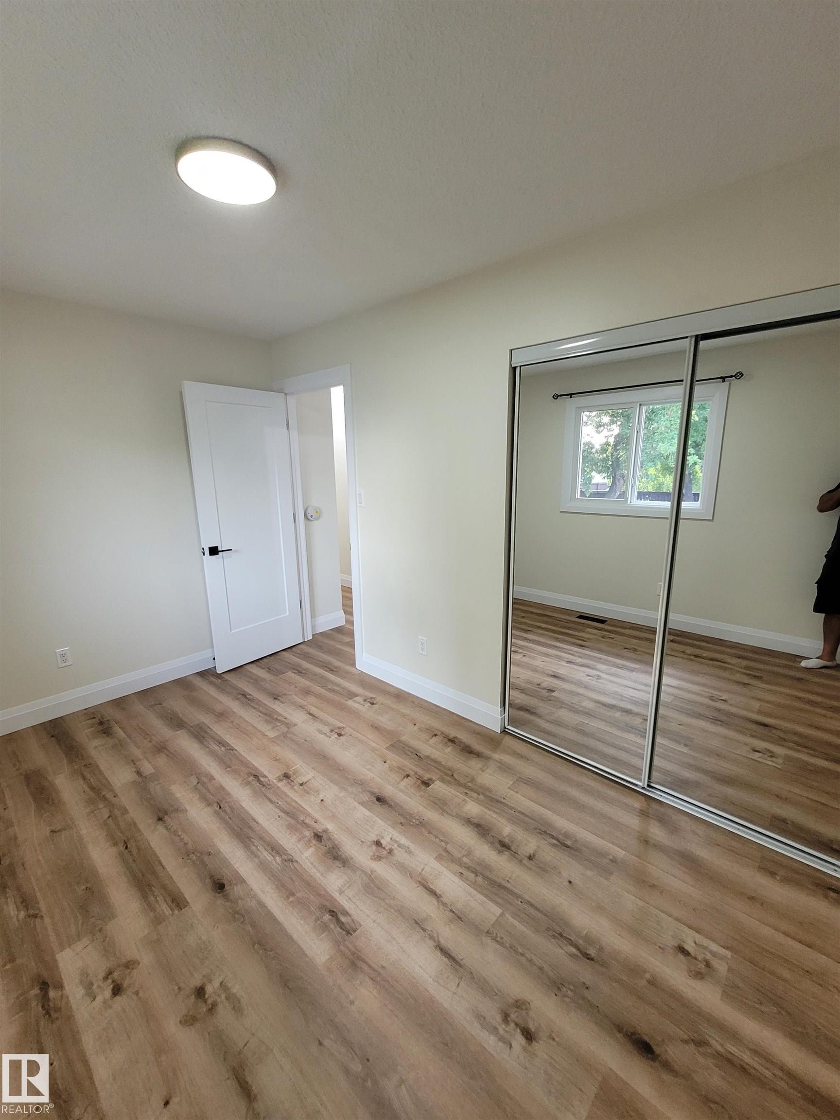 Wood-finish flooring, white walls, white doors, and a ceiling-mounted light fixture - 2412 80 Street Nw, Edmonton, AB