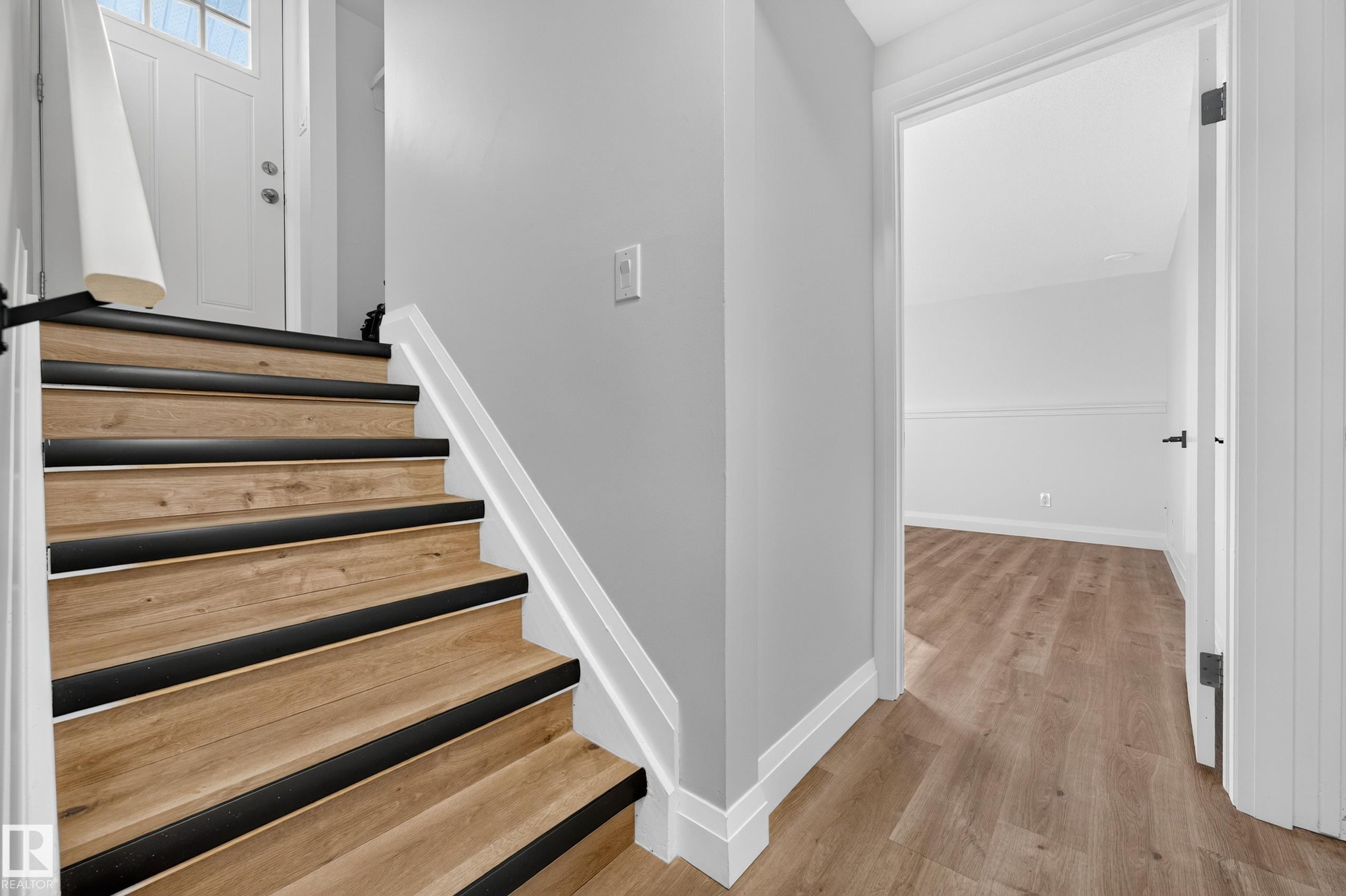 Wood-finish staircase with black treads and white risers, complementing light wood-finish flooring - 2412 80 Street Nw, Edmonton, AB