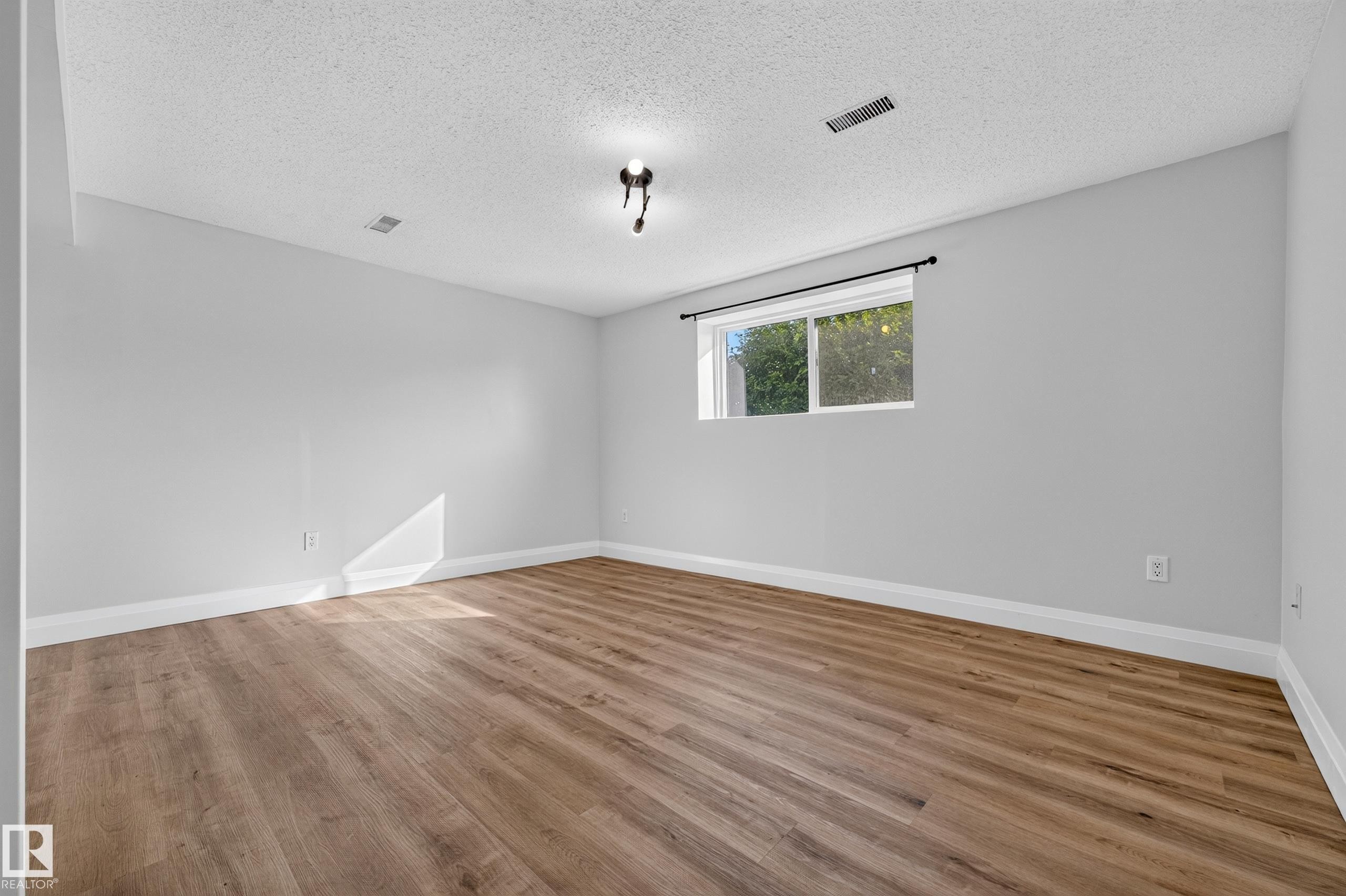 Wood-finish flooring, white walls, and a window with a black curtain rod - 2412 80 Street Nw, Edmonton, AB