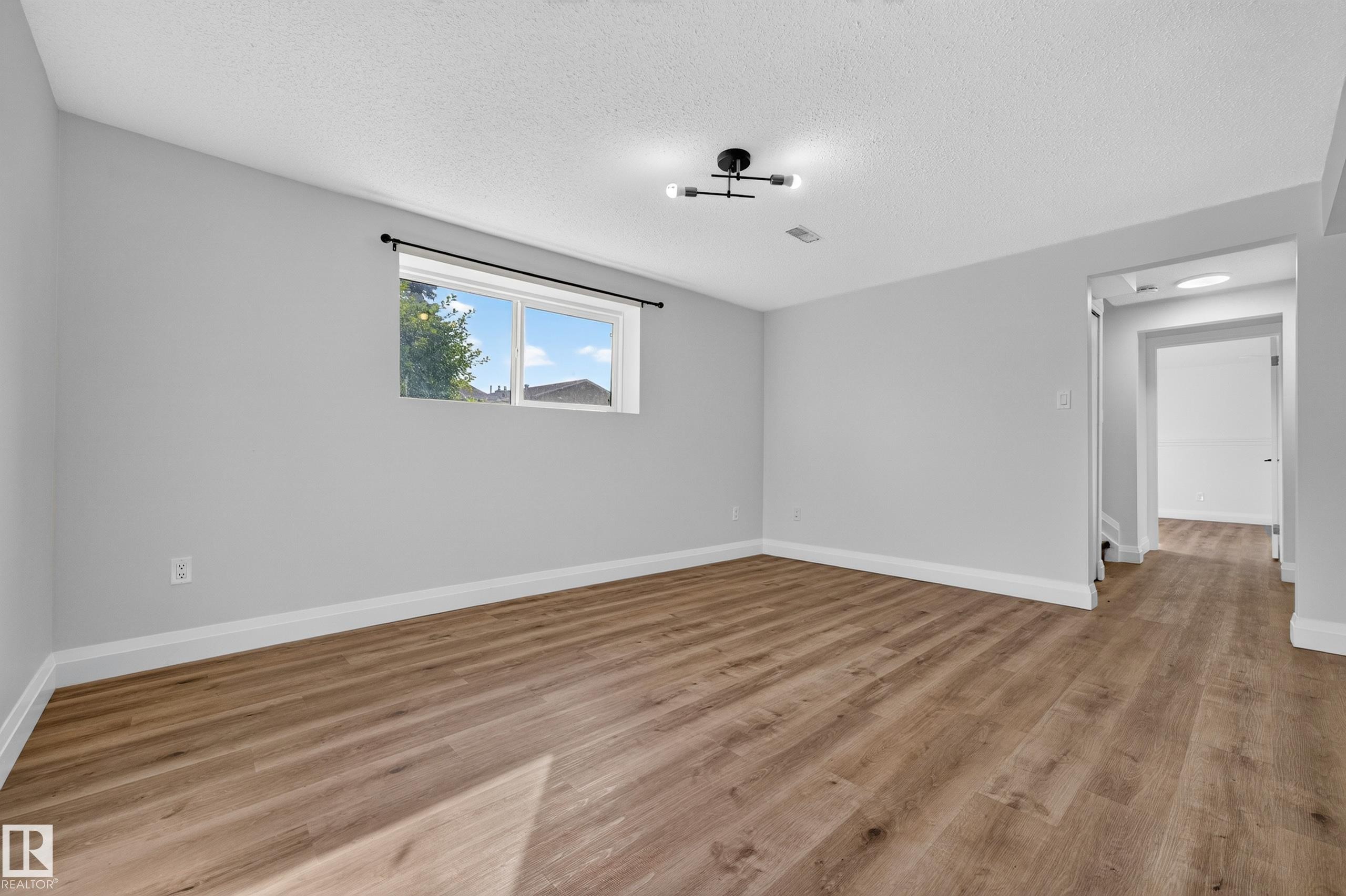 Recessed window with white trim, wood-finish flooring, light gray wall paint, and a contemporary ceiling light fixture - 2412 80 Street Nw, Edmonton, AB