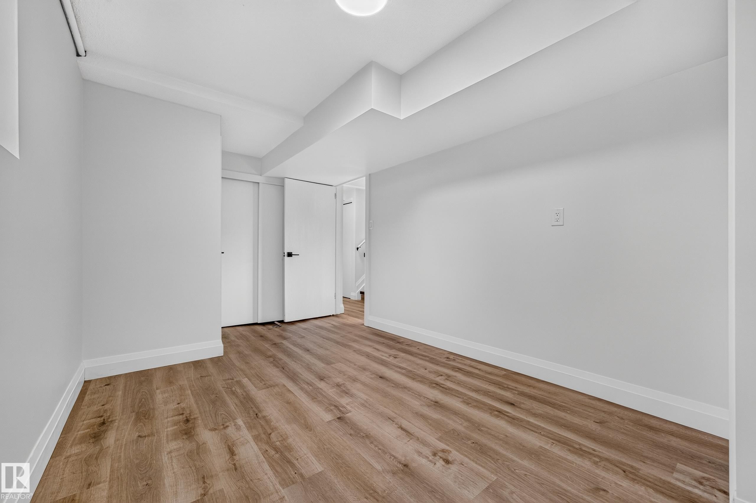 Wood-finish flooring with white trim, recessed lighting, and white interior doors with black hardware - 2412 80 Street Nw, Edmonton, AB
