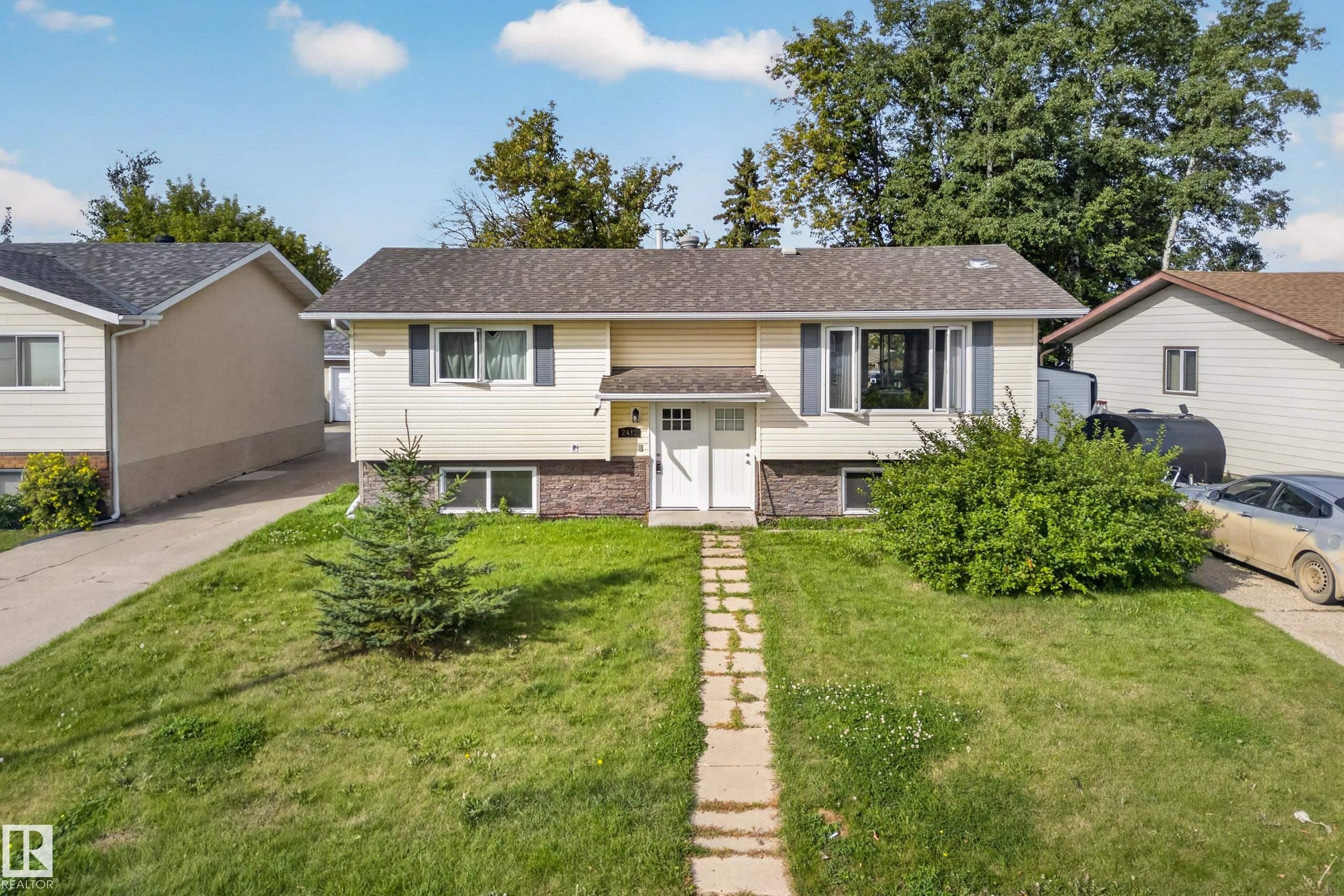 Split-level residence featuring vinyl siding, brick accents, and a shingled roof - 2412 80 Street Nw, Edmonton, AB