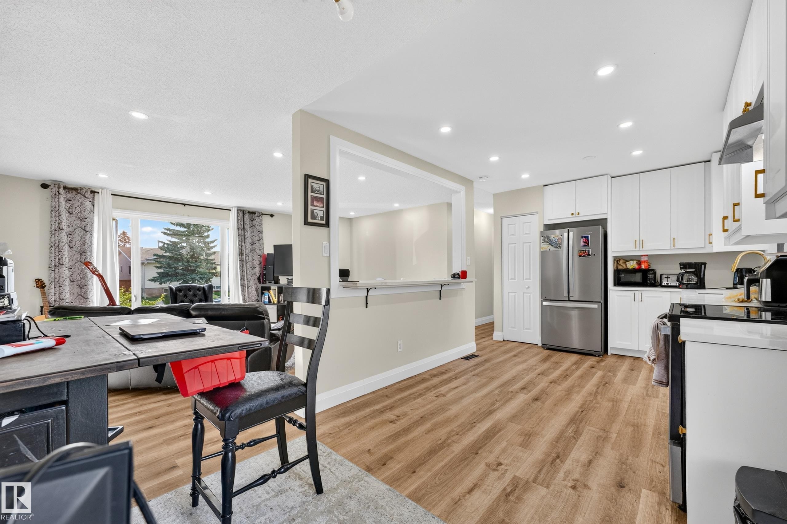 Kitchen with white cabinetry, stainless steel appliances, and wood-finish flooring - 2412 80 Street Nw, Edmonton, AB