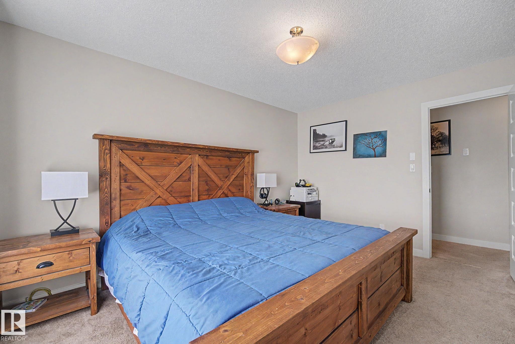 Bedroom featuring neutral wall paint, textured carpet flooring, and a flush-mount ceiling light fixture - 3343 Weidle Way Sw, Edmonton, AB